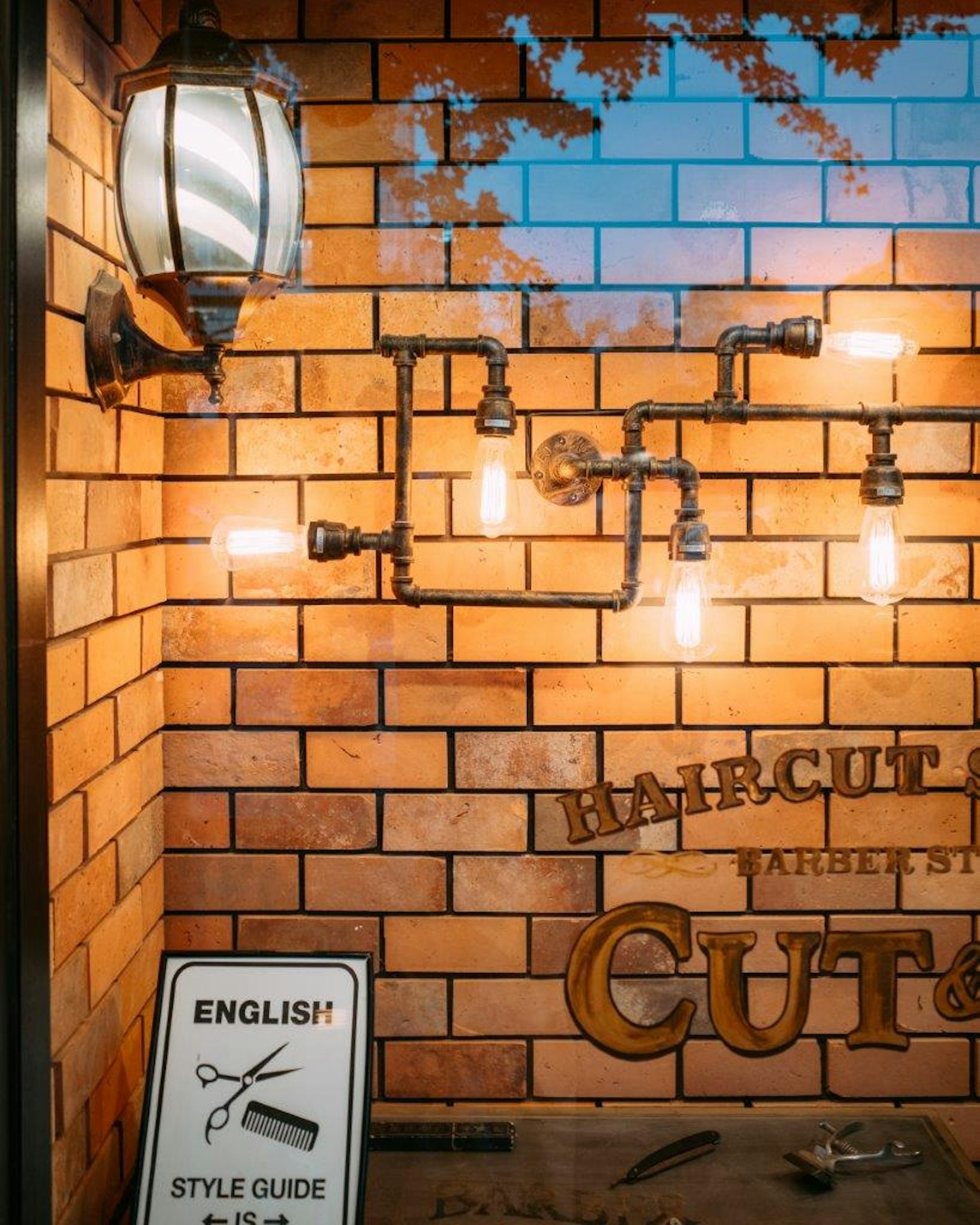 ภายนอกของร้านตัดผมที่มีไฟพายและป้ายบนผนังอิฐ
