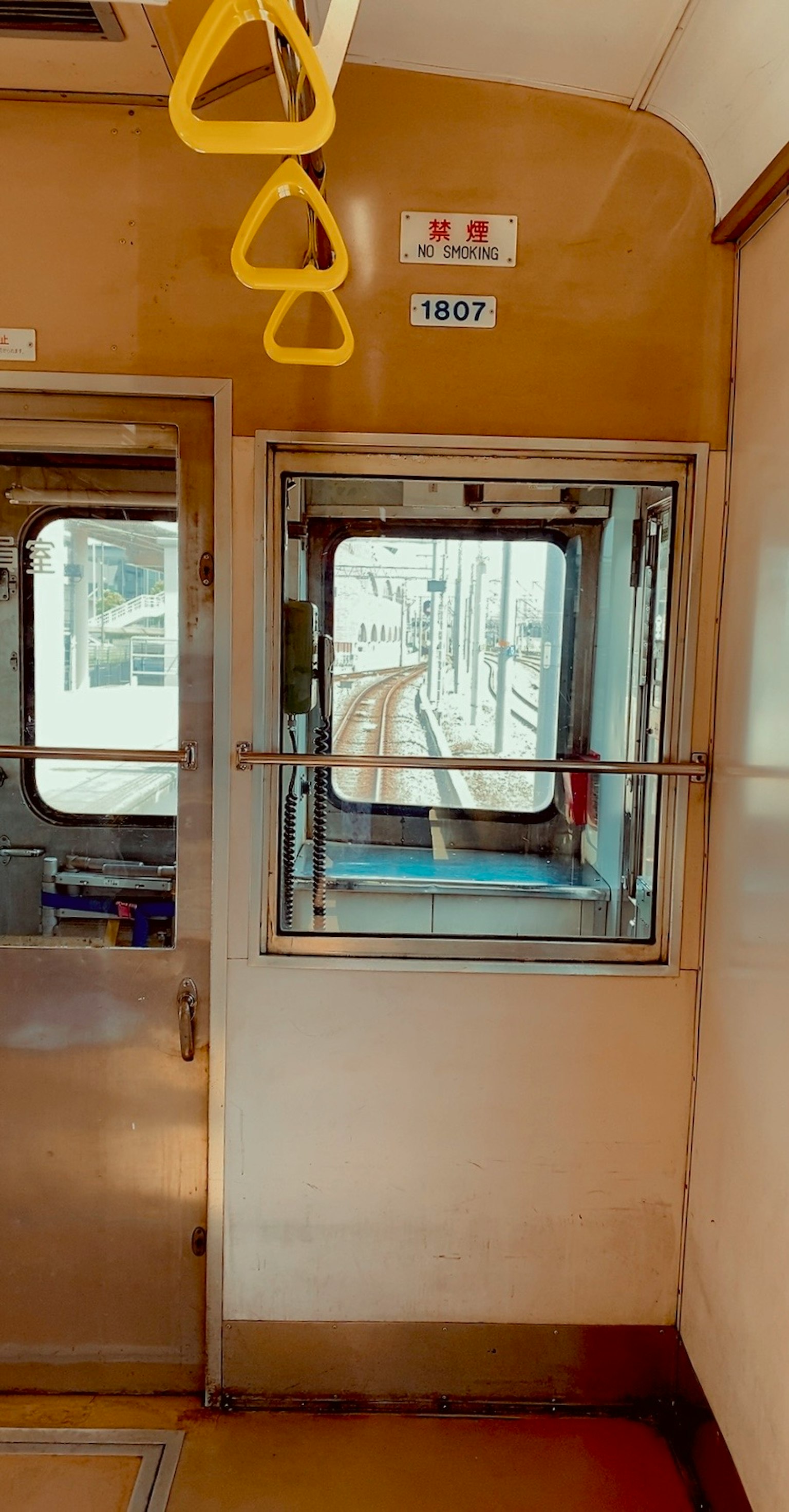 Innensicht eines Zugabteils mit einem Fenster und den Gleisen draußen