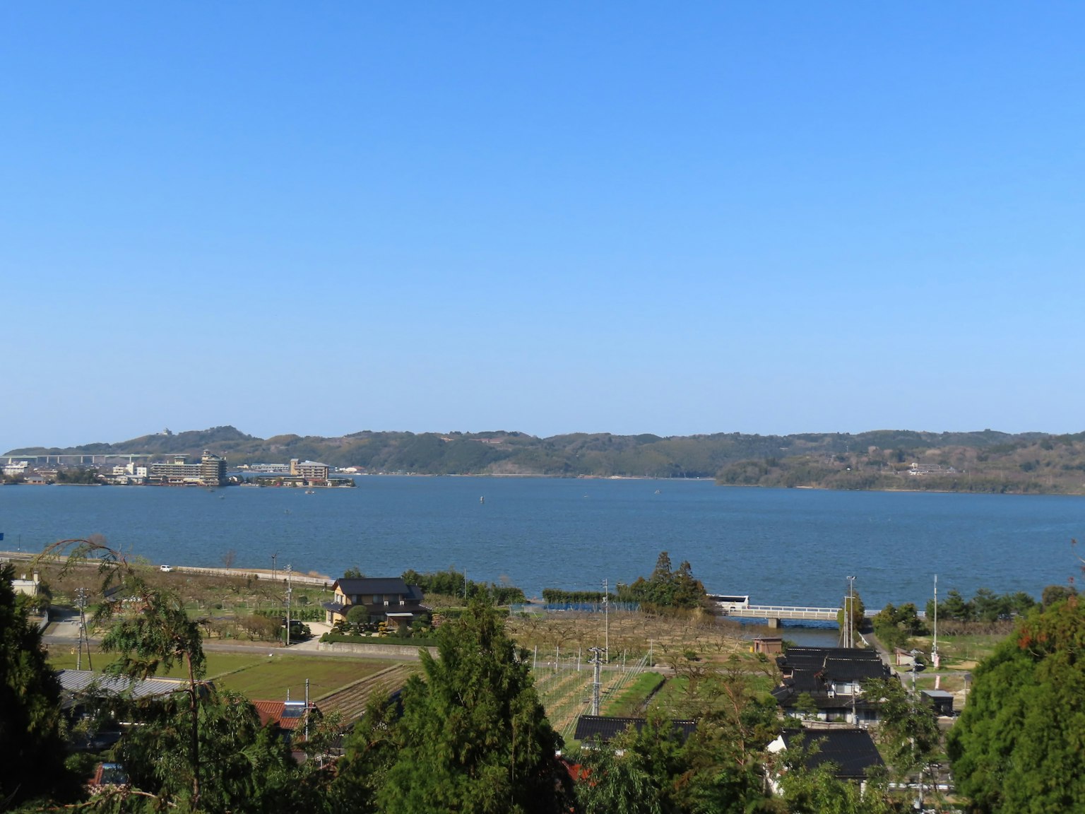 藍天和寧靜海洋的風景 附近有房屋和綠色樹木