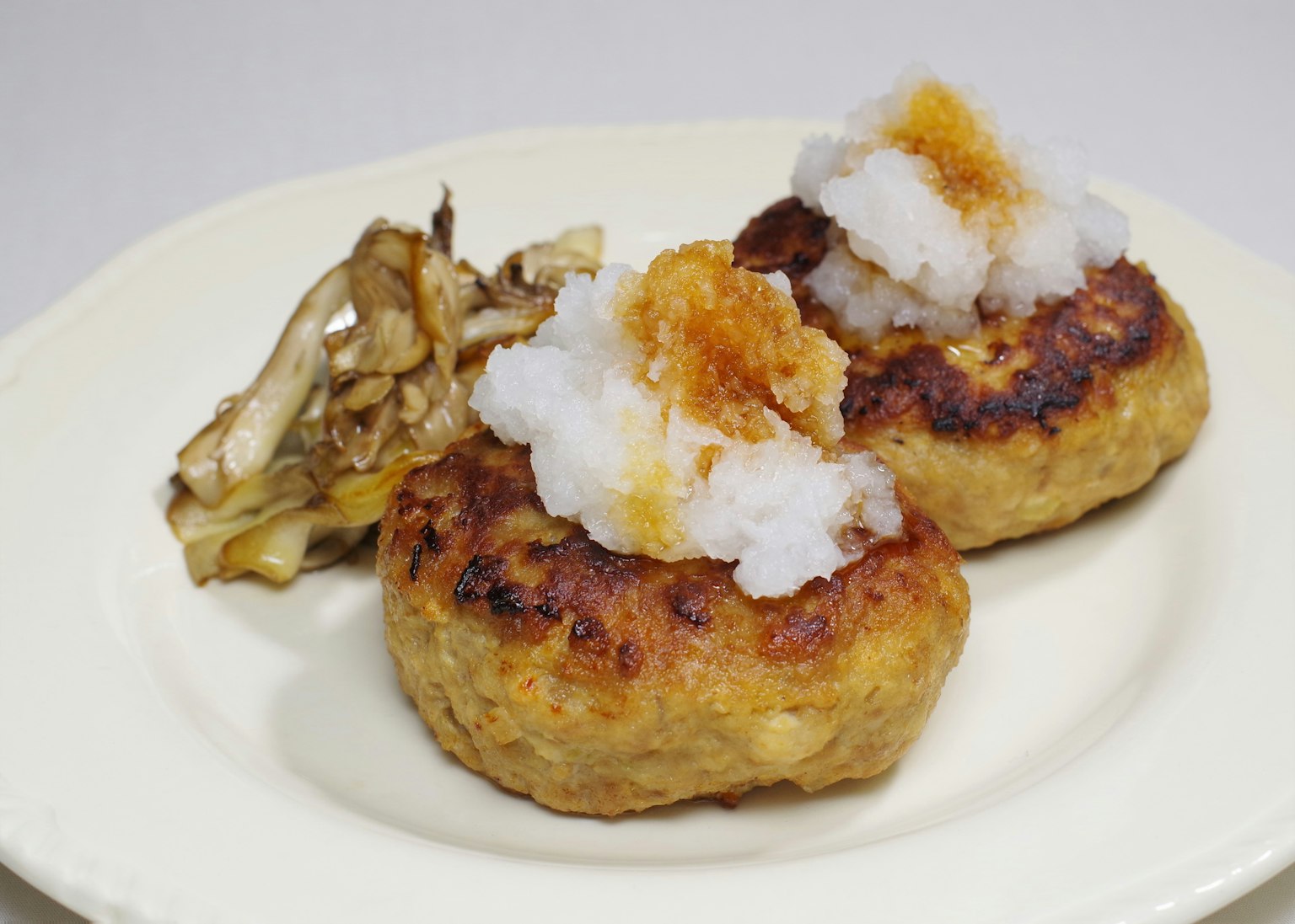 Due hamburger guarniti con daikon grattugiato serviti con contorno di funghi