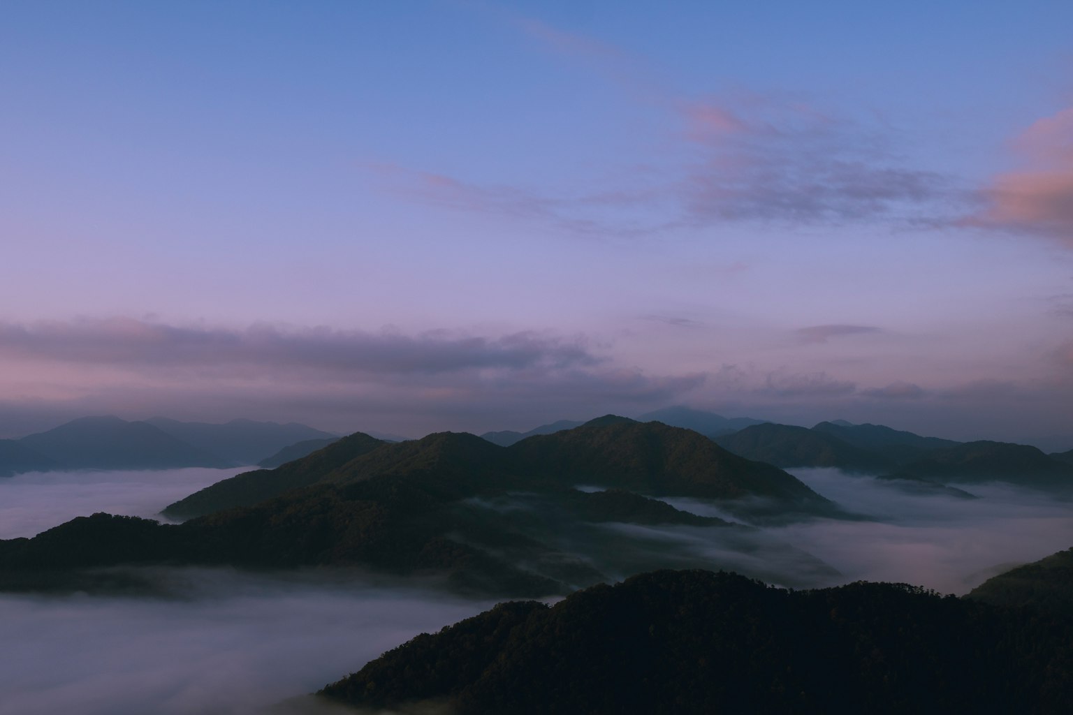 Scenic view of mountains shrouded in mist with a blue and purple sky