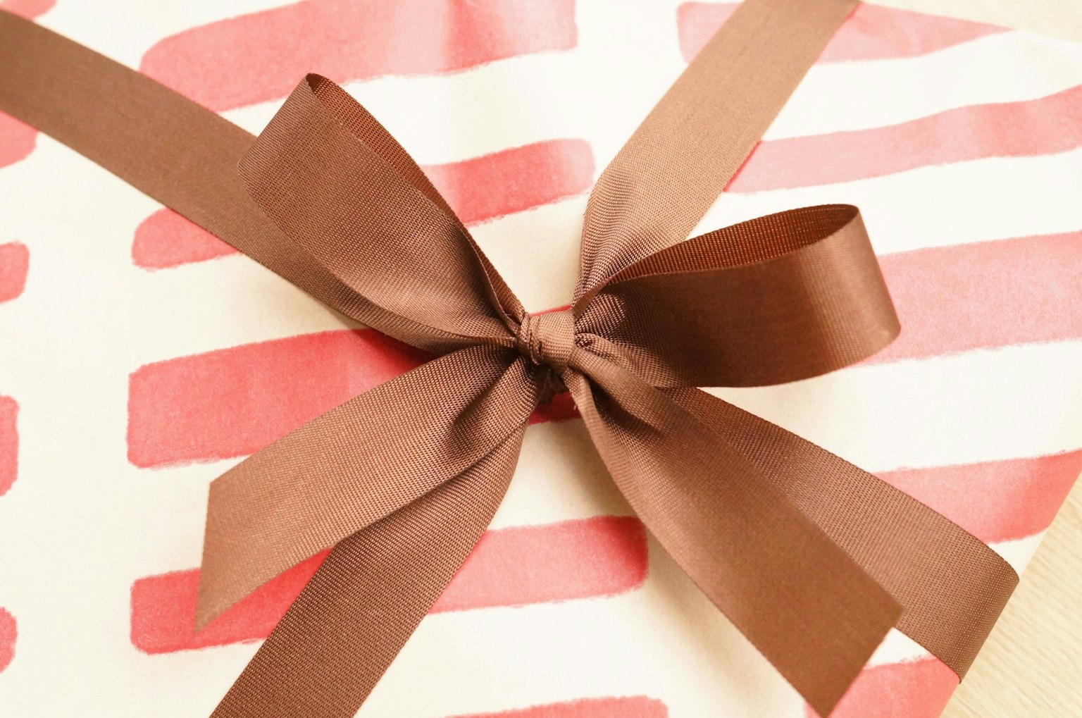 Geschenk eingewickelt in rosa gestreiftem Papier mit braunem Band