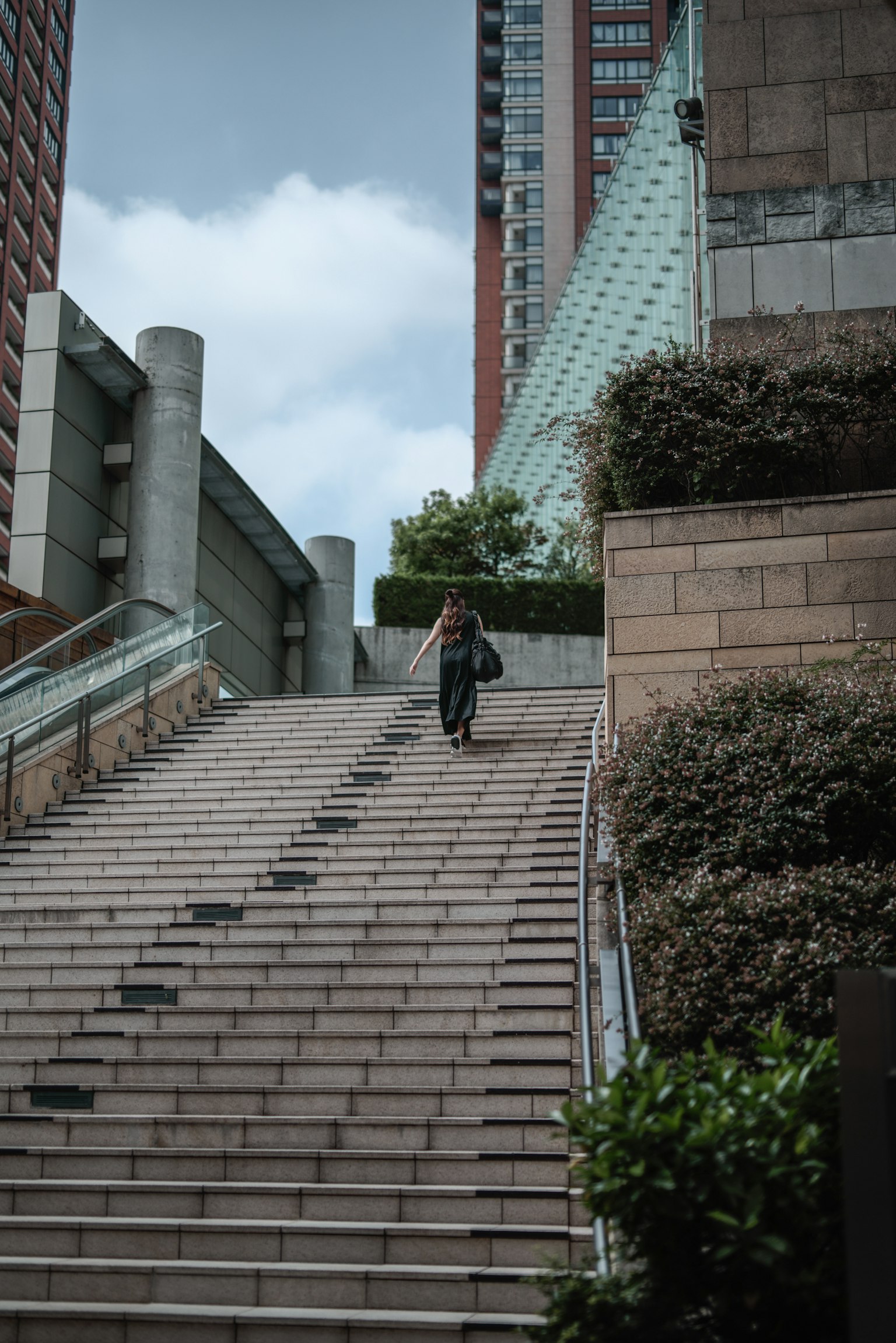 Person fährt mit dem Fahrrad eine Treppe hinunter vor moderner Architektur