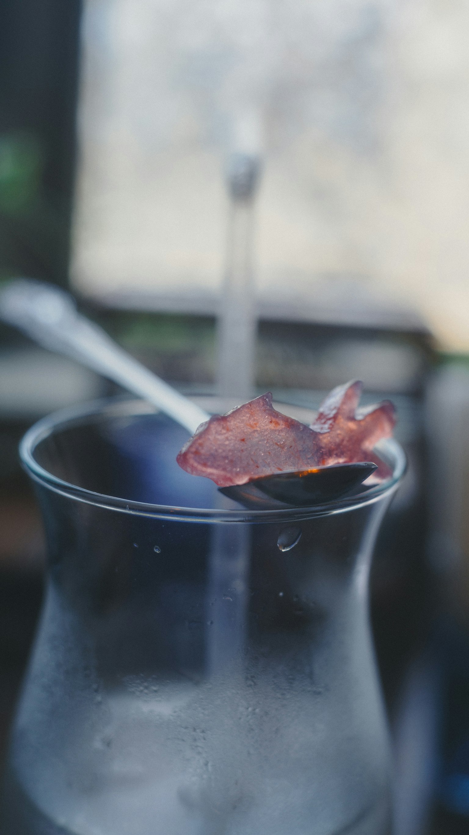 透明なグラスに氷とスプーンがあり、上に花びらが乗っている