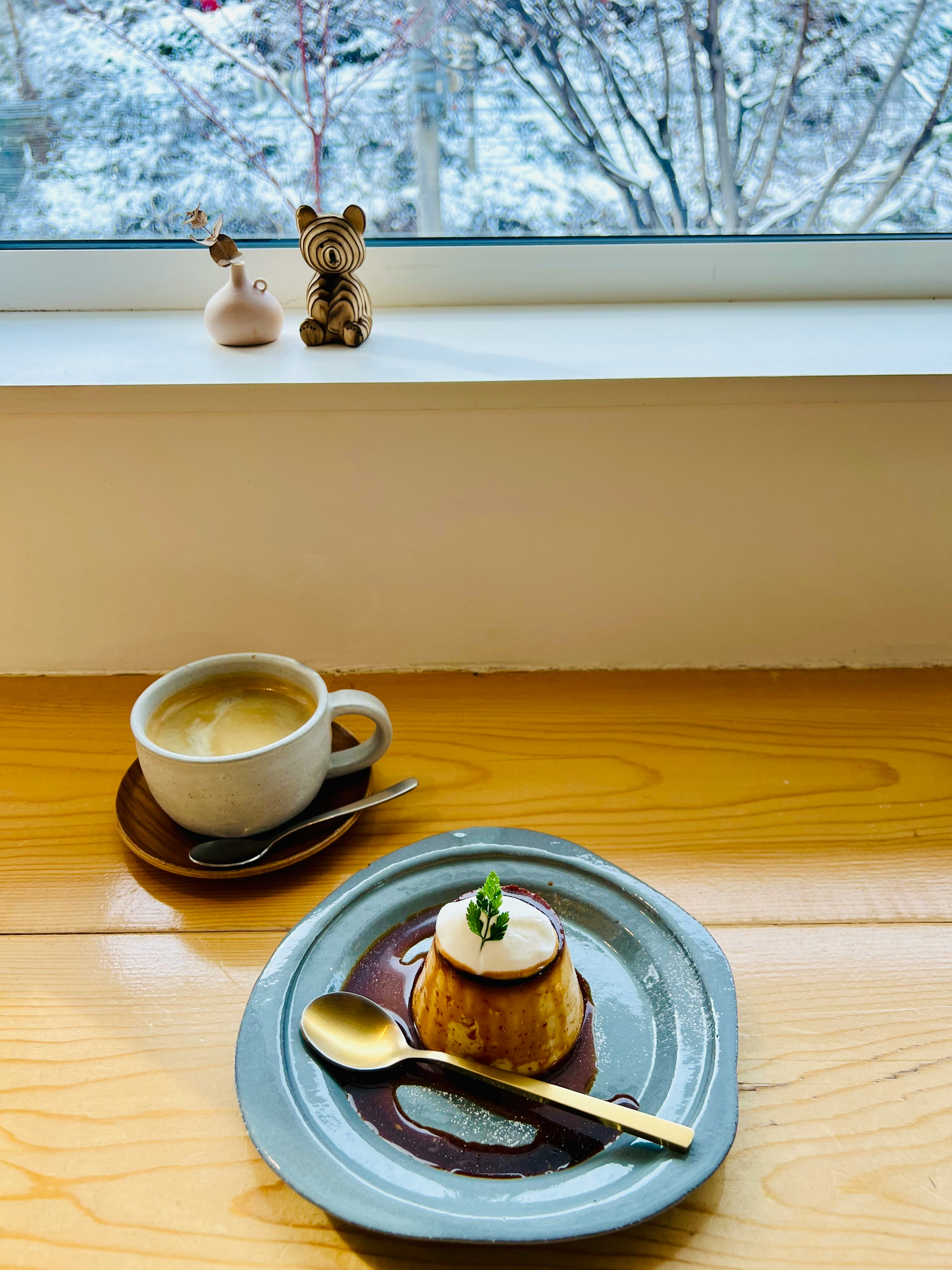 窓辺の木製テーブルで楽しむプリンとコーヒーの冬のひとり飯