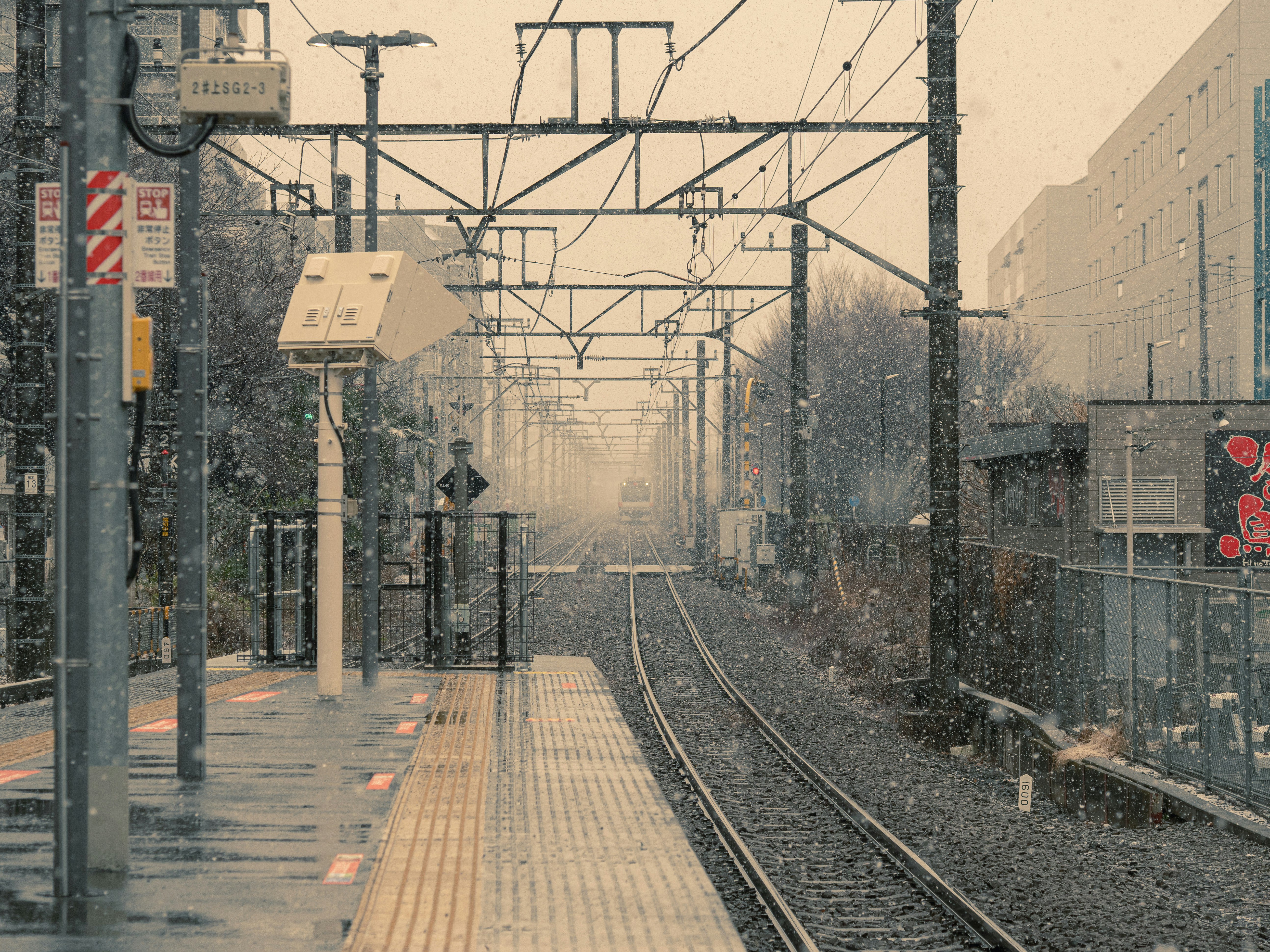 雪の降る線路沿いの街並み
