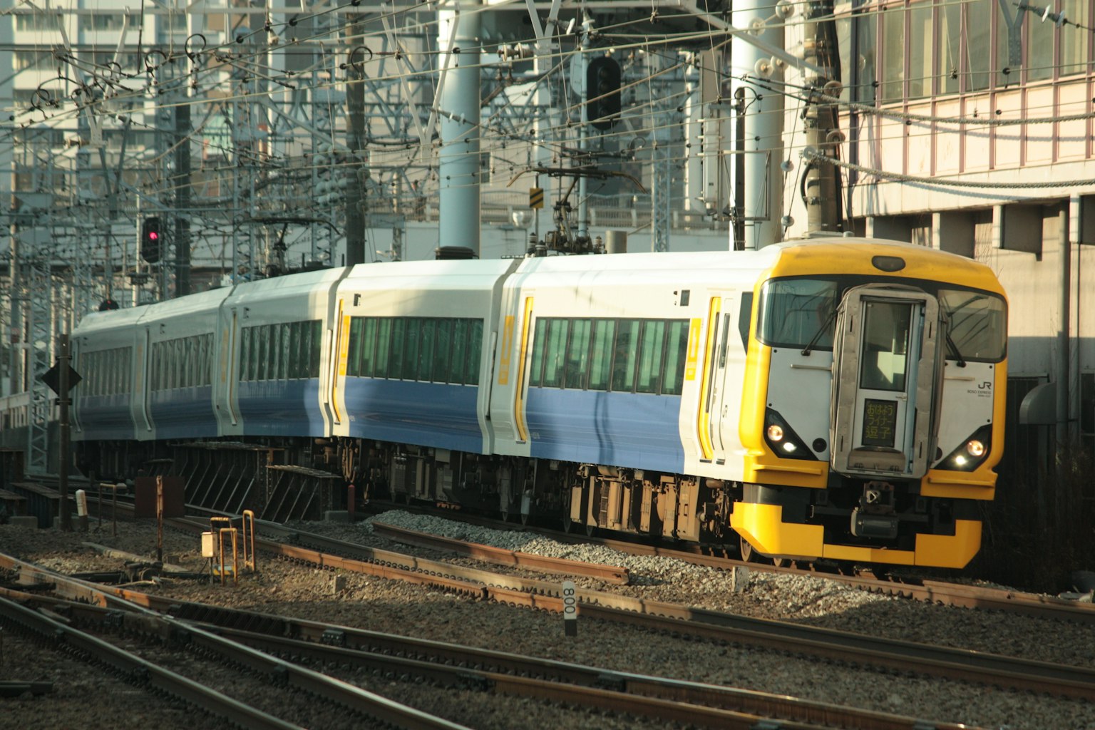 Kereta dengan bodi kuning dan biru yang melaju di rel