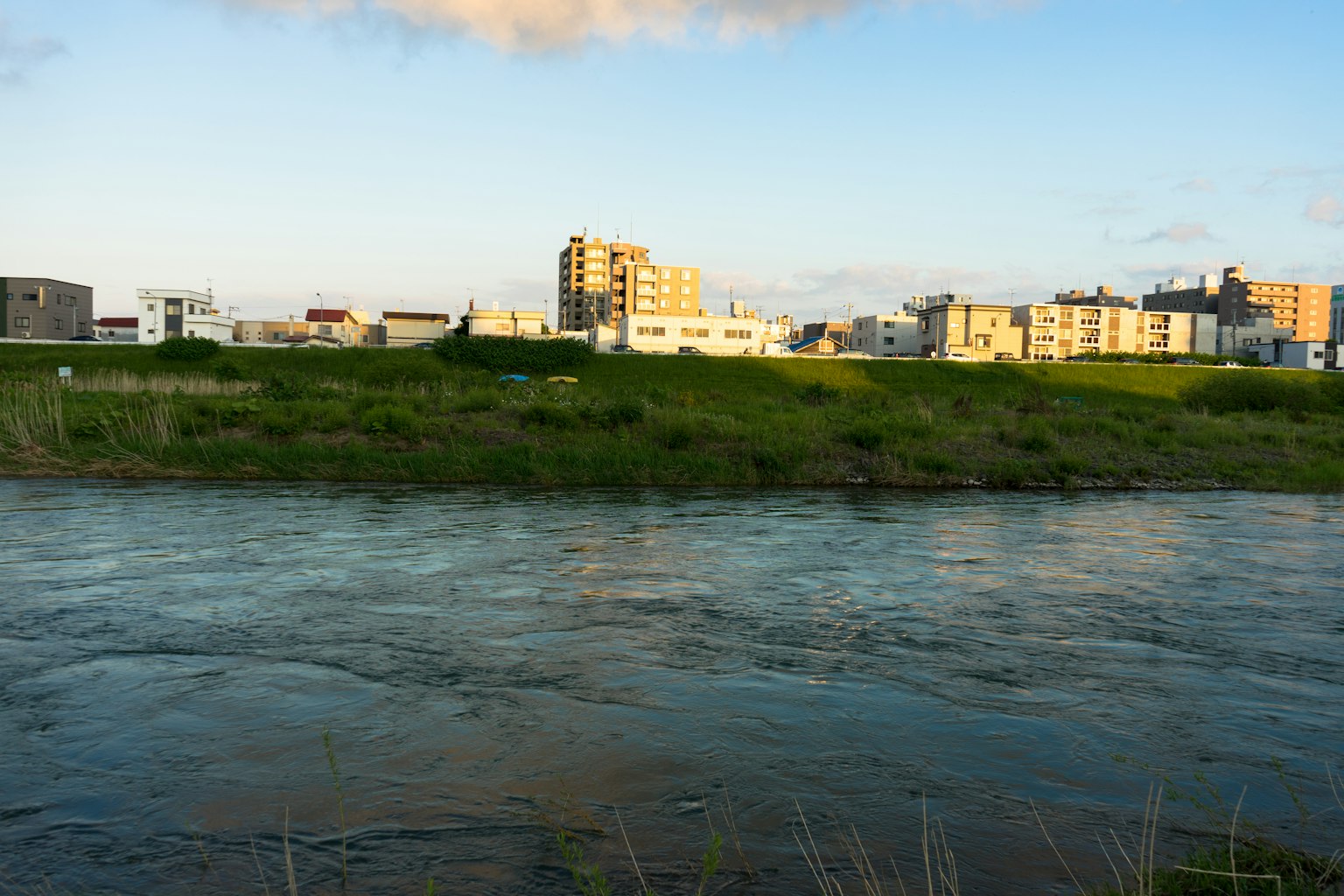 Pemandangan kota di dekat sungai dengan langit biru dan awan