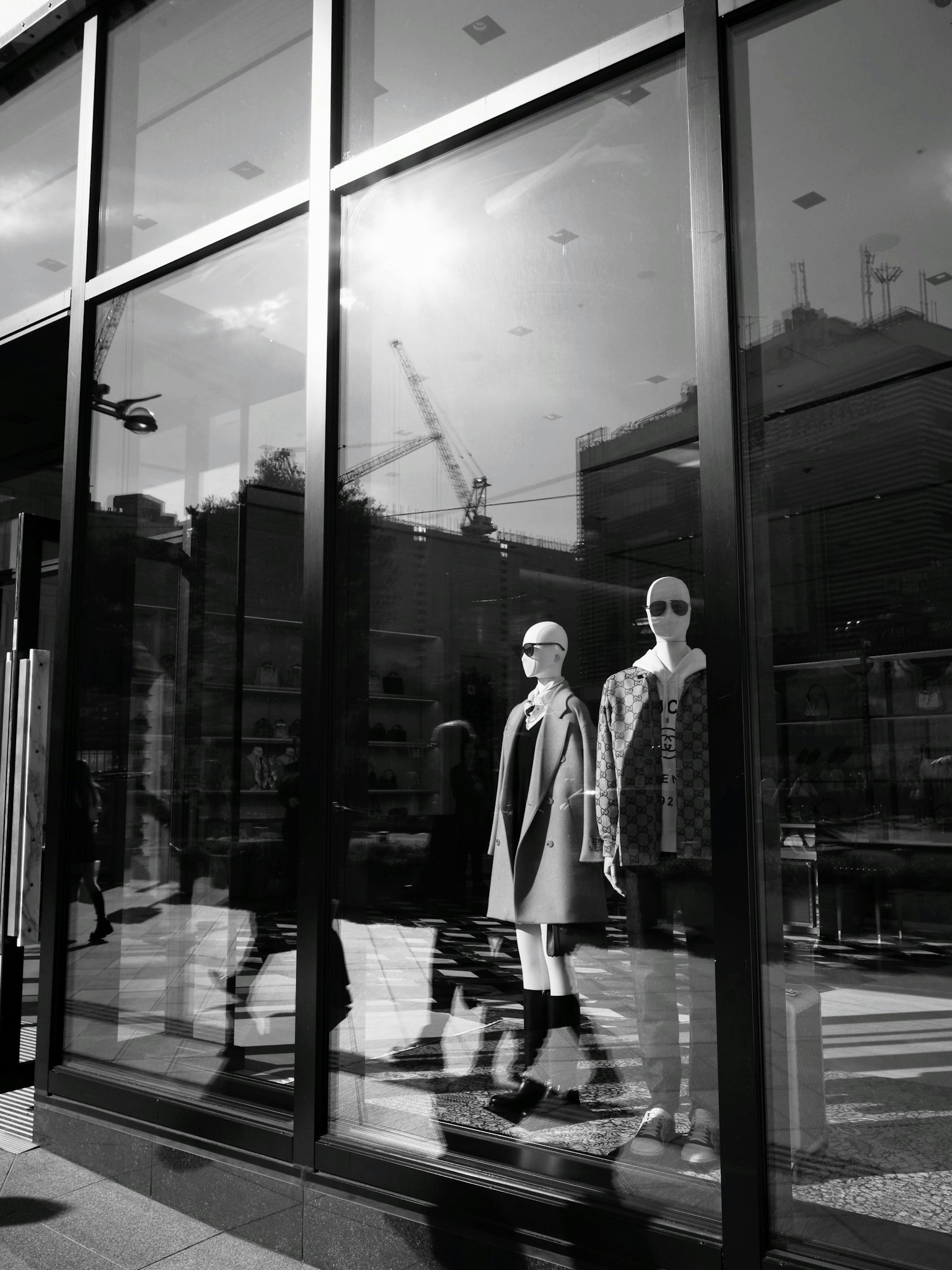 สองหุ่นจำลองในหน้าต่างร้านสีดำและขาวพร้อมกับการสะท้อนของเมือง