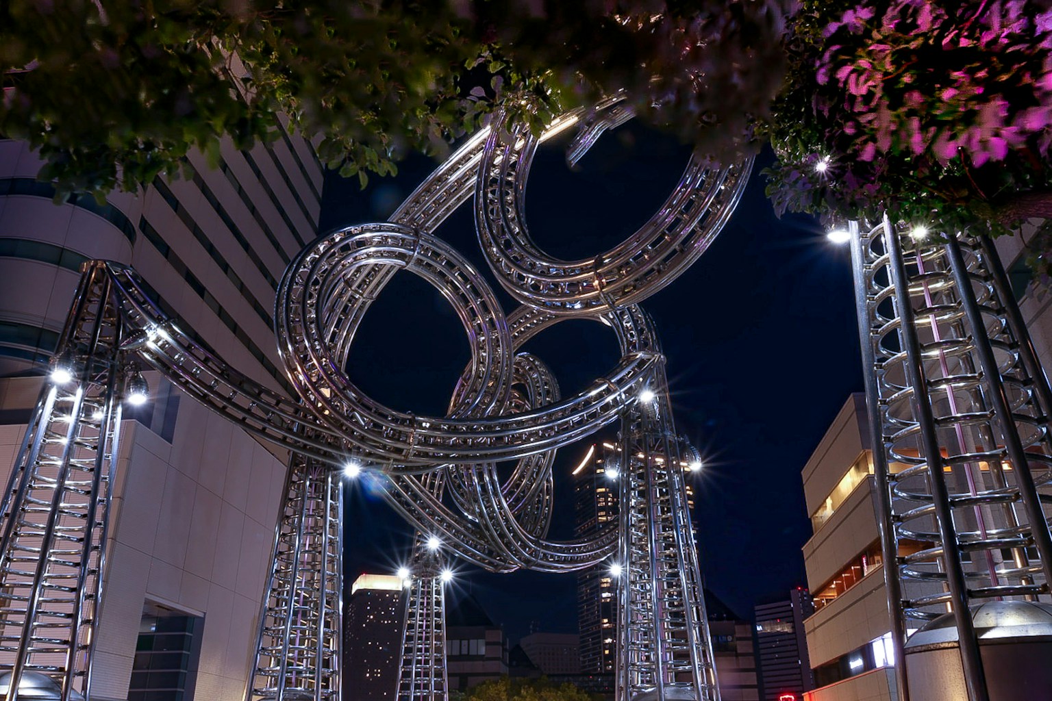 Installation artistique métallique illuminée la nuit avec des structures circulaires entrelacées