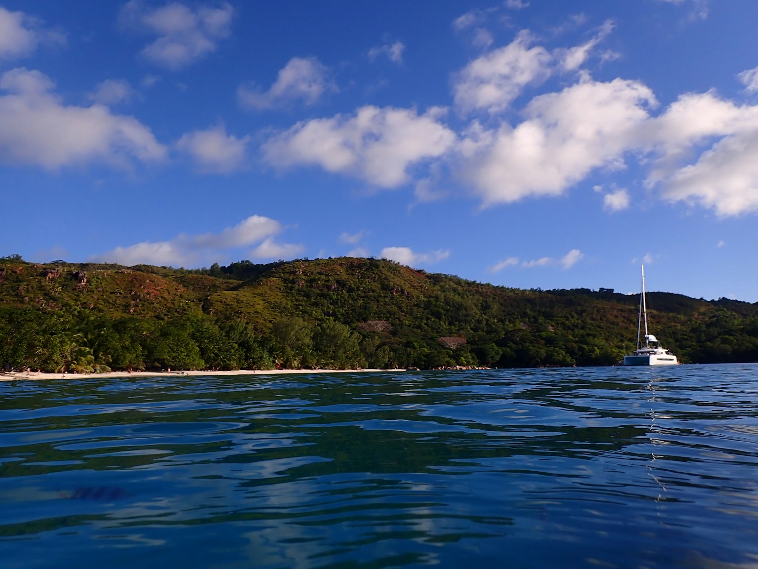 Pemandangan indah yacht di atas air biru dengan bukit hijau di latar belakang