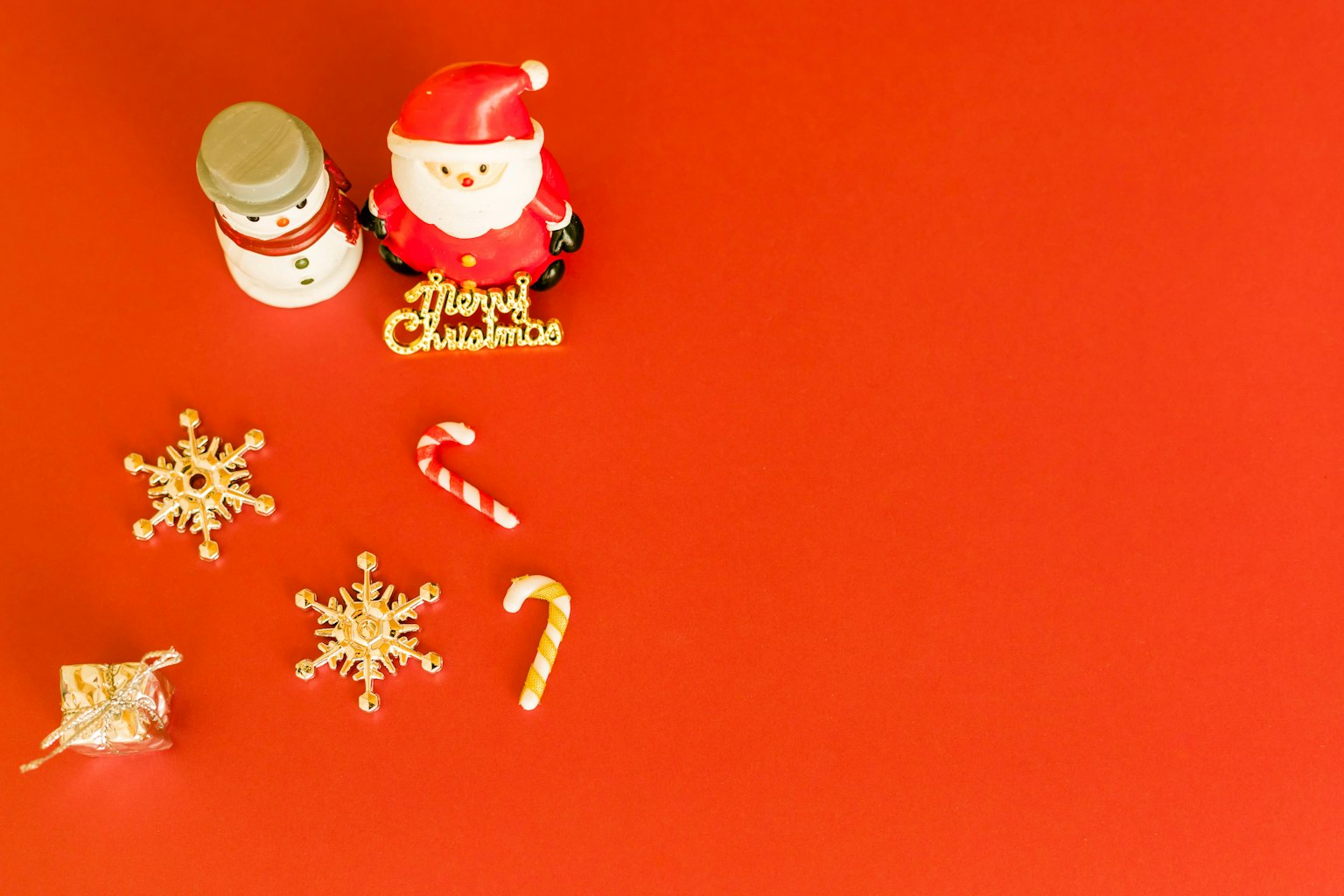 Figurine Santa Claus dan figurine manusia salju di latar belakang merah dengan dekorasi Natal