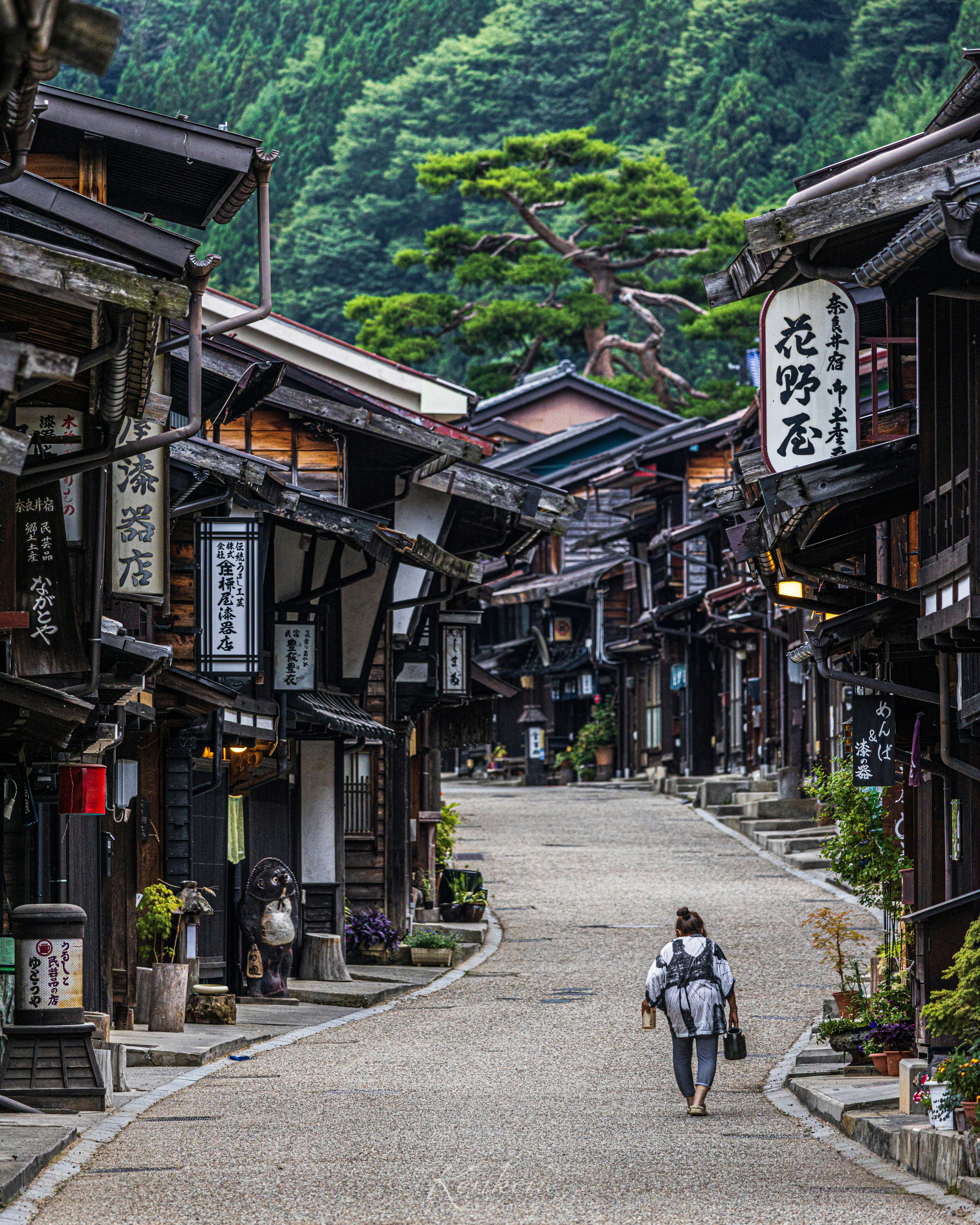 山あいの古い町並みを歩く人と石畳の路地