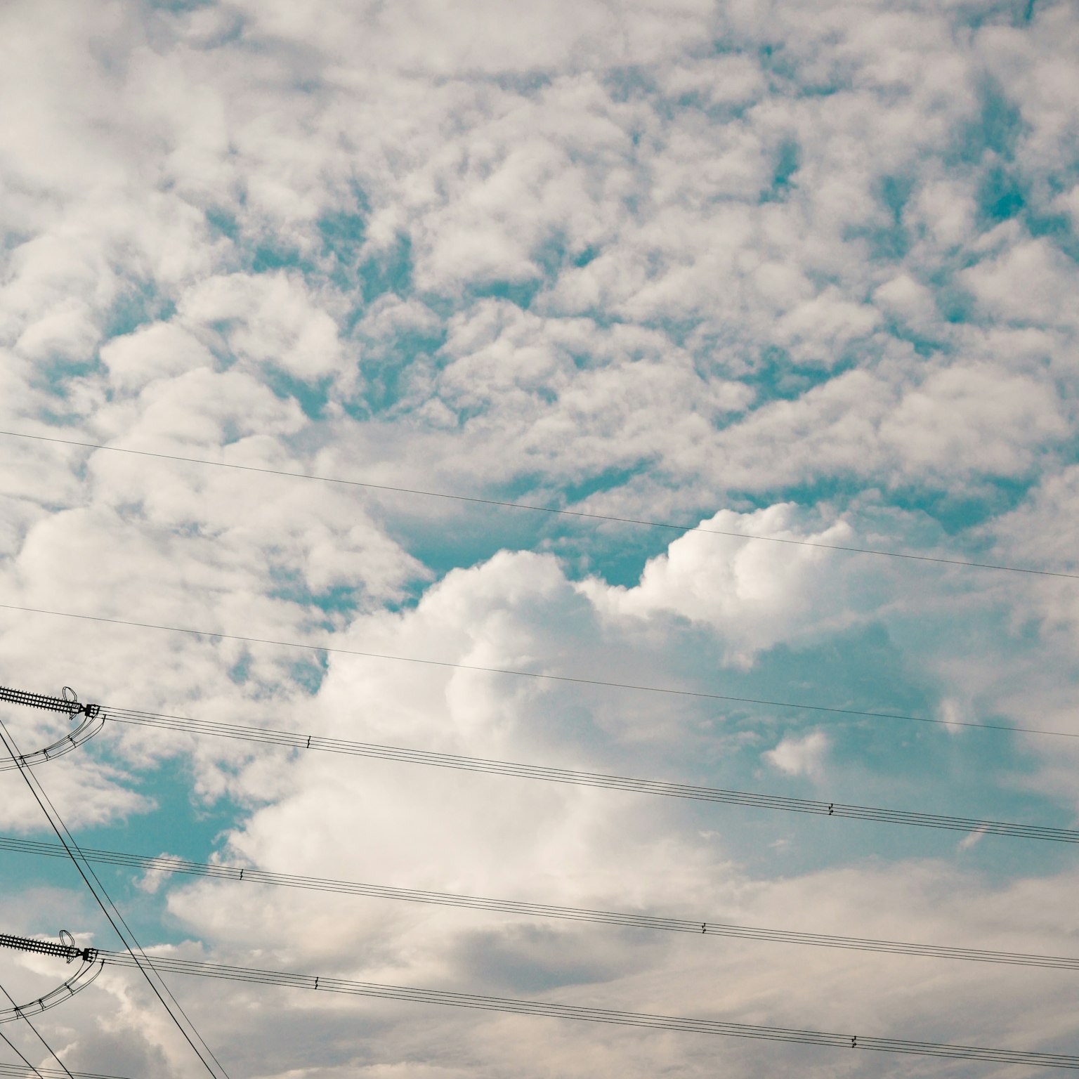 Blue sky with white clouds and visible power lines