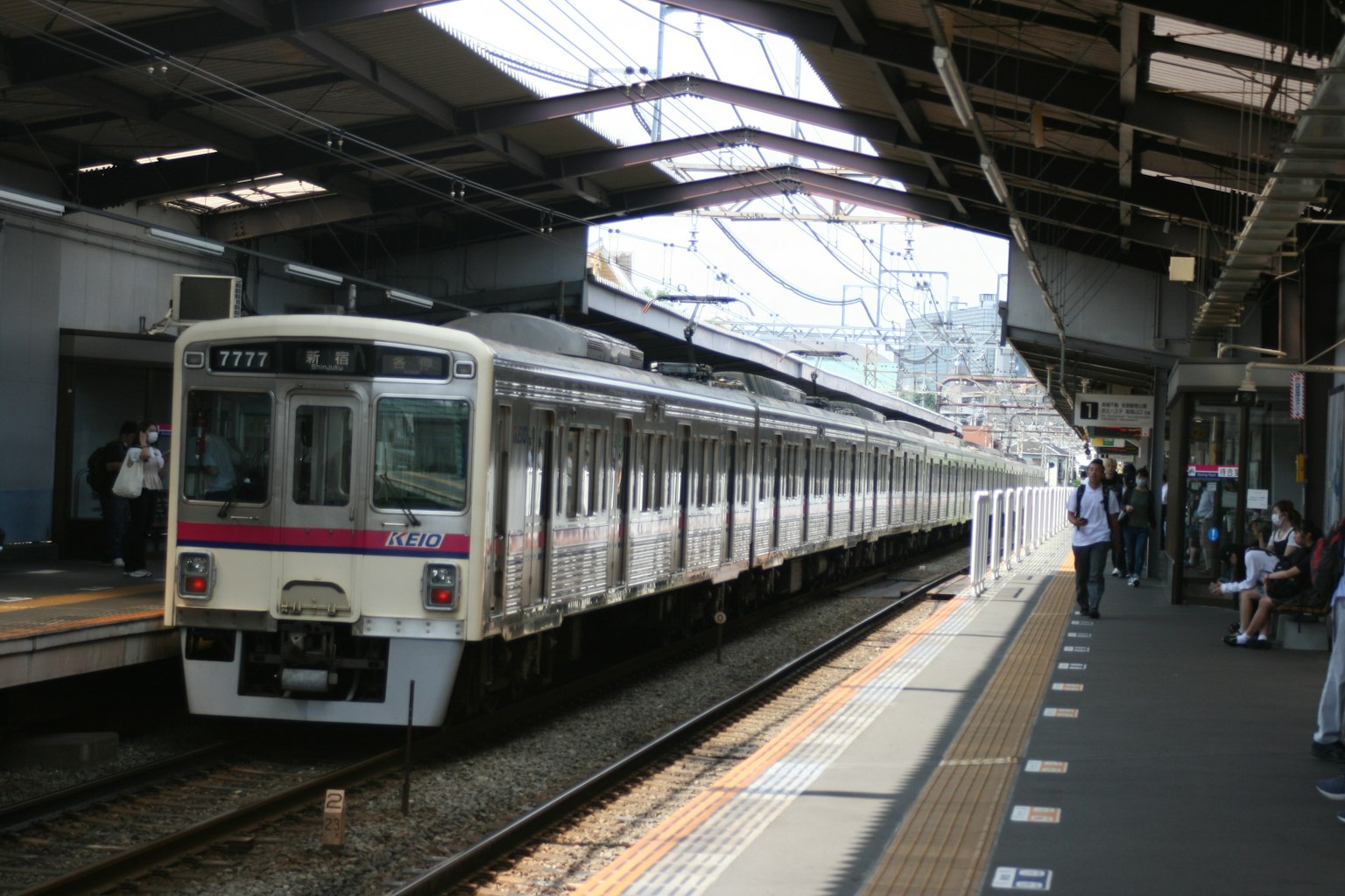 Kereta berhenti di stasiun dengan penumpang menunggu