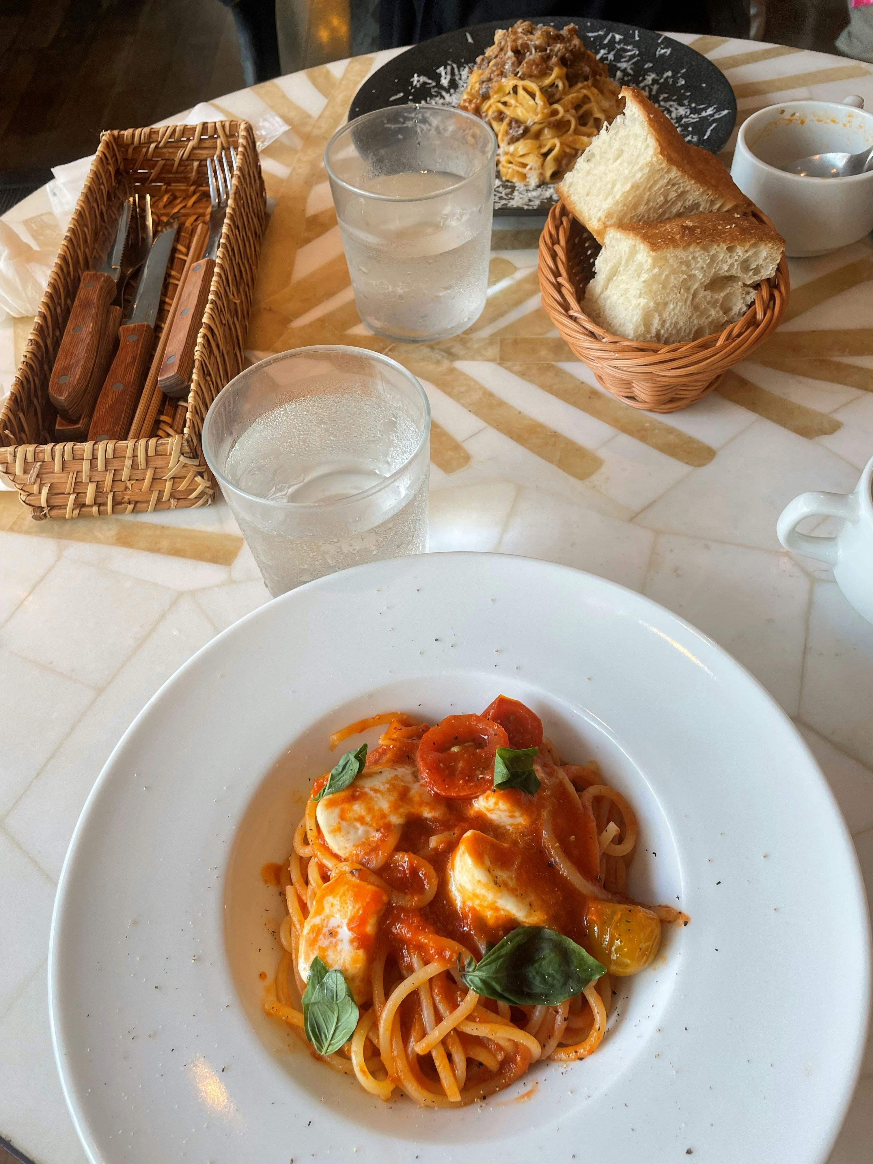 assiettes de pâtes, pain et boissons sur une table
