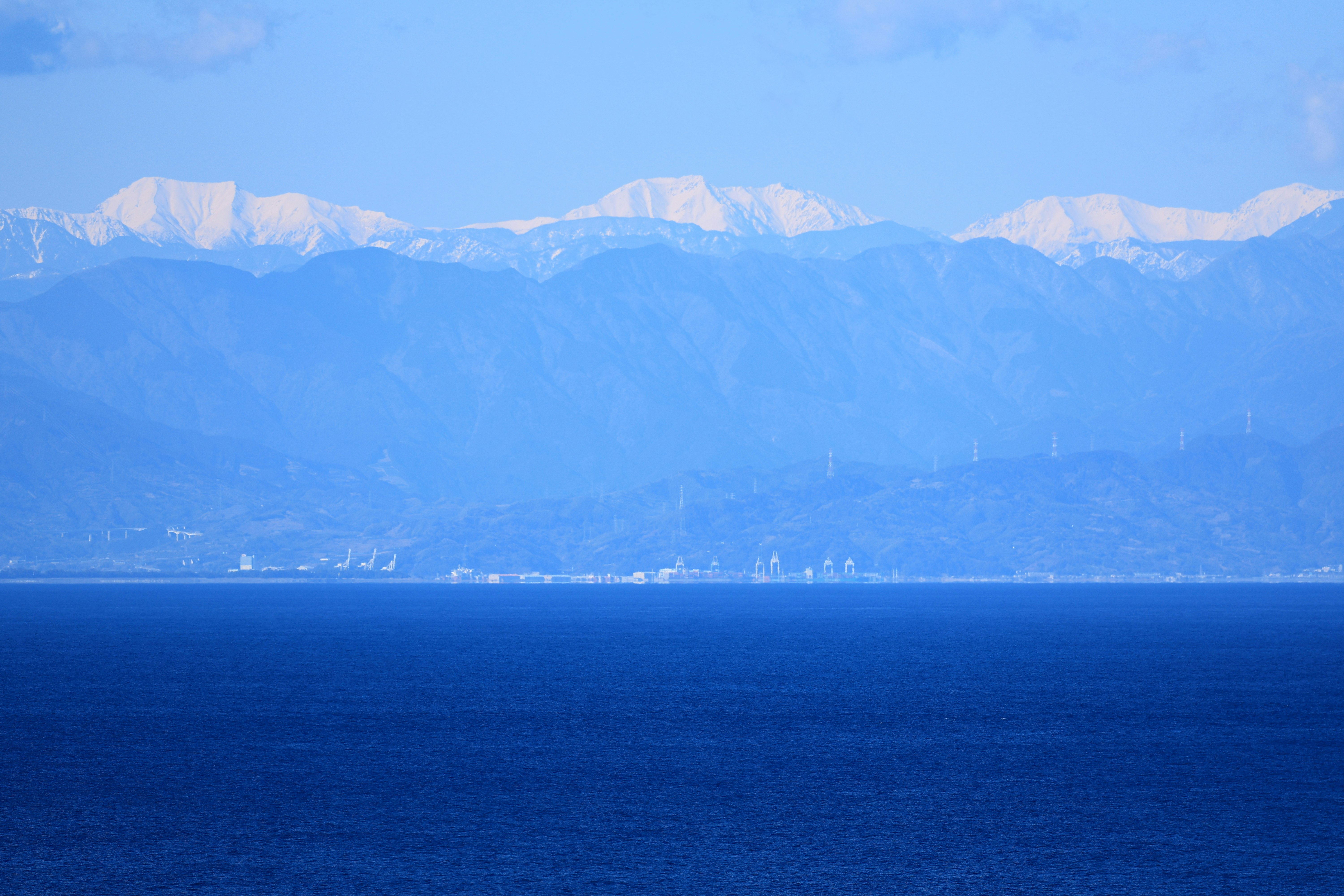 駿河湾の海越しに清水港と雪の南アルプスが望める景色