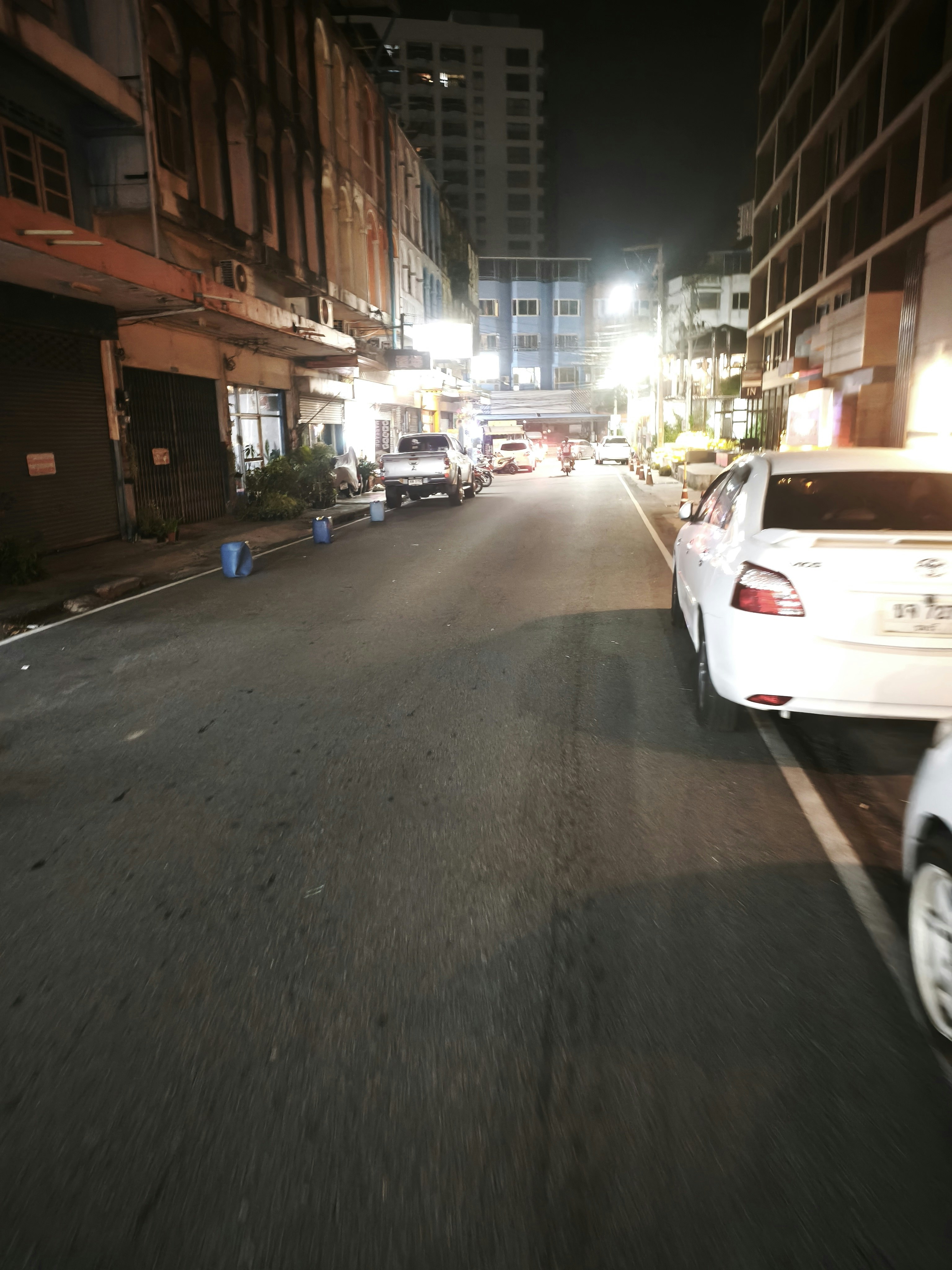 夜の路地に並ぶ車と商店街の看板