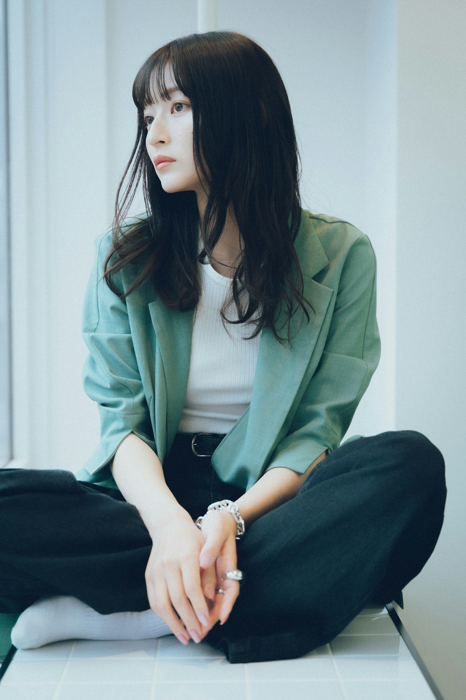 Une femme portant une veste verte assise près d'une fenêtre