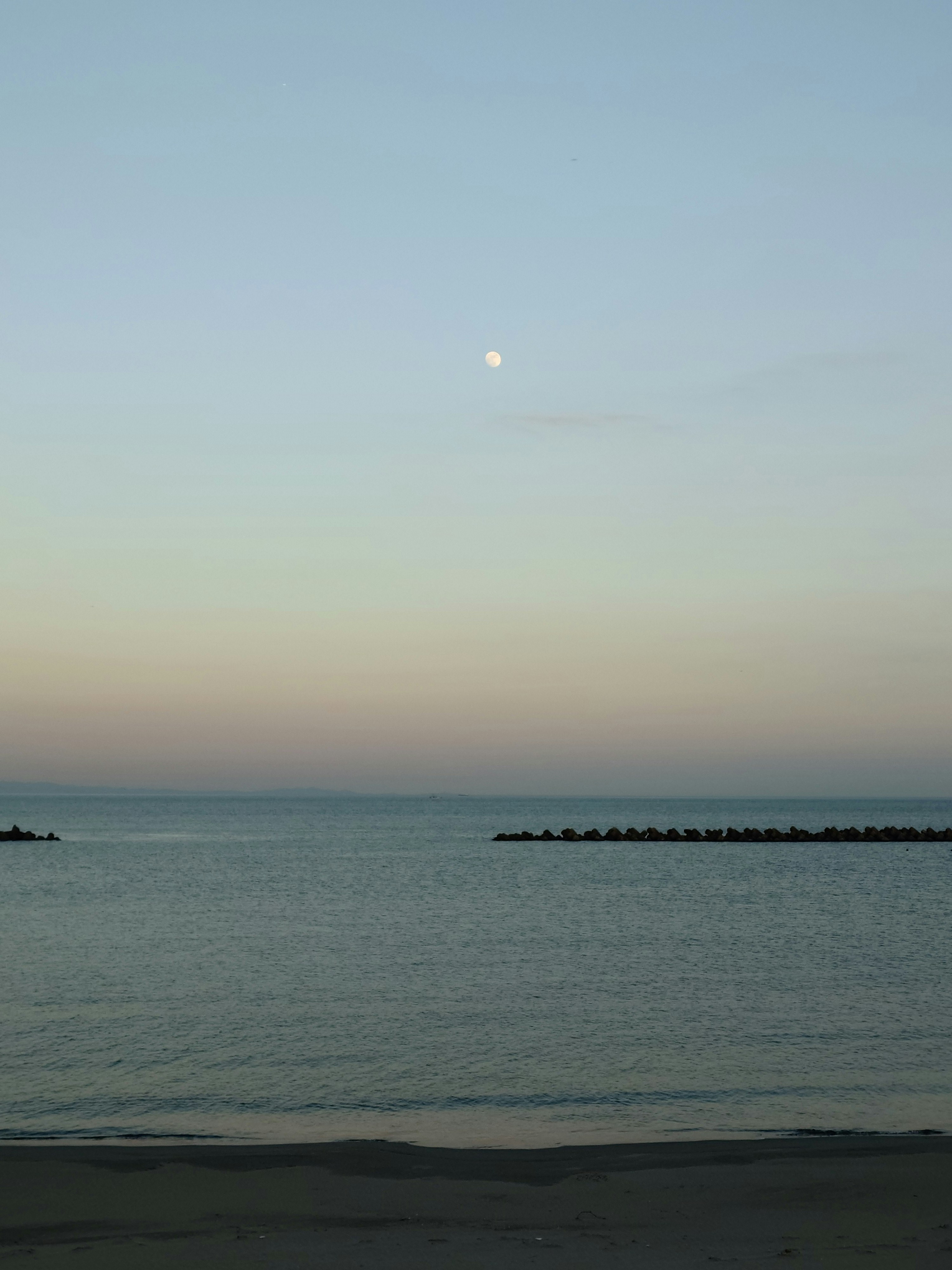 マジックアワーの海辺に浮かぶ月