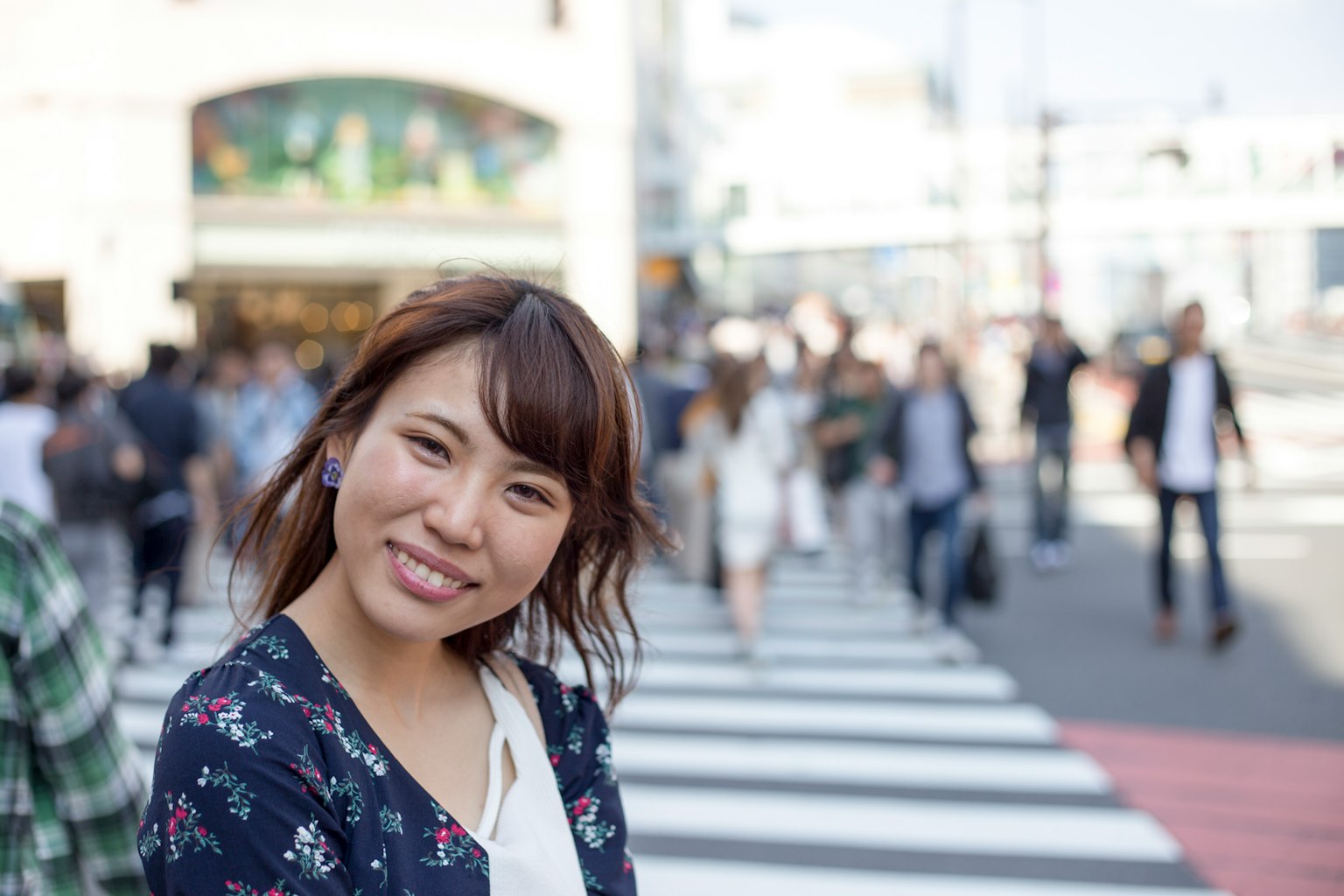Woman smiling on a crosswalk surrounded by pedestrians