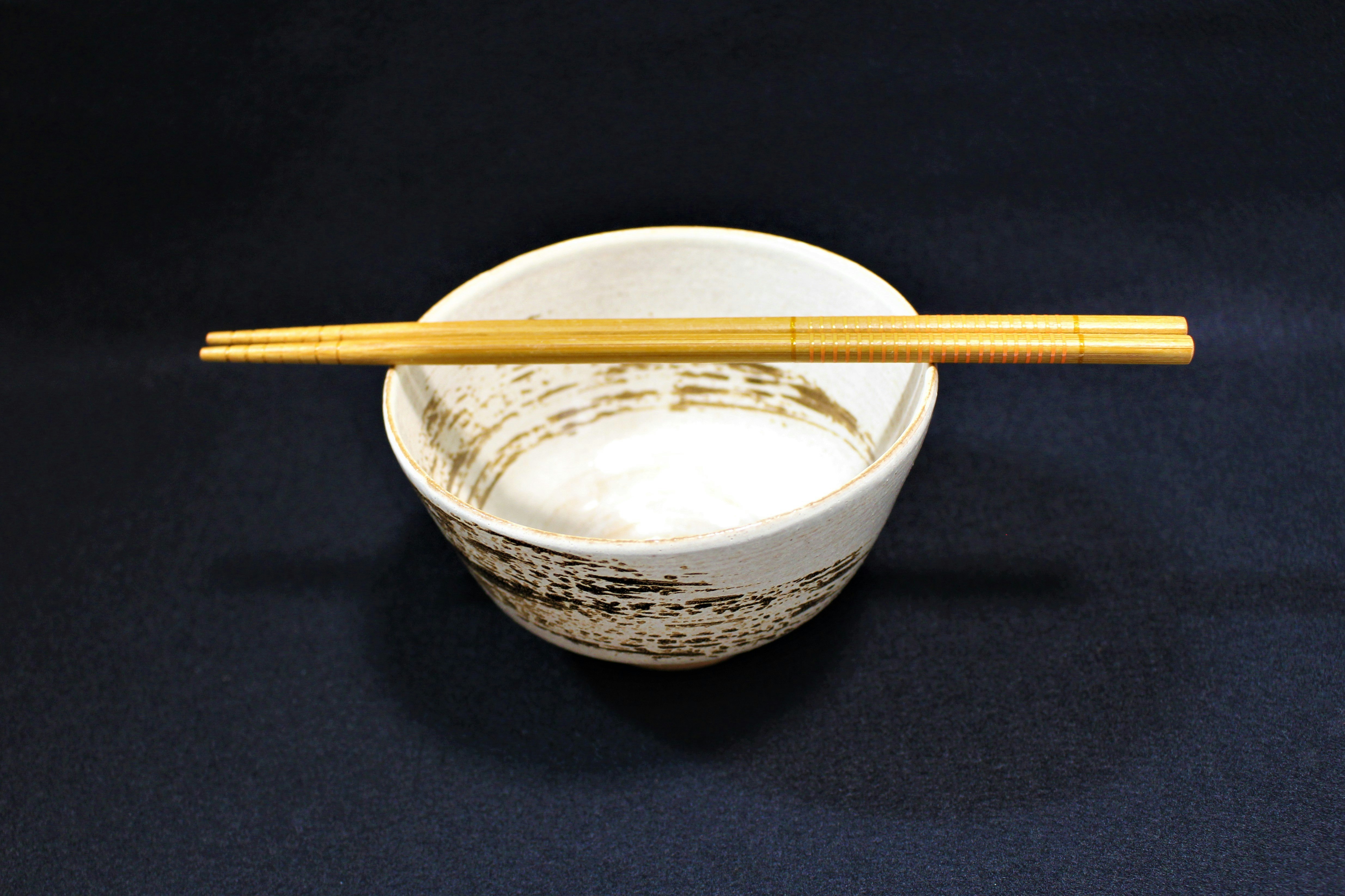 黒背景の器に盛られた箸と白いご飯