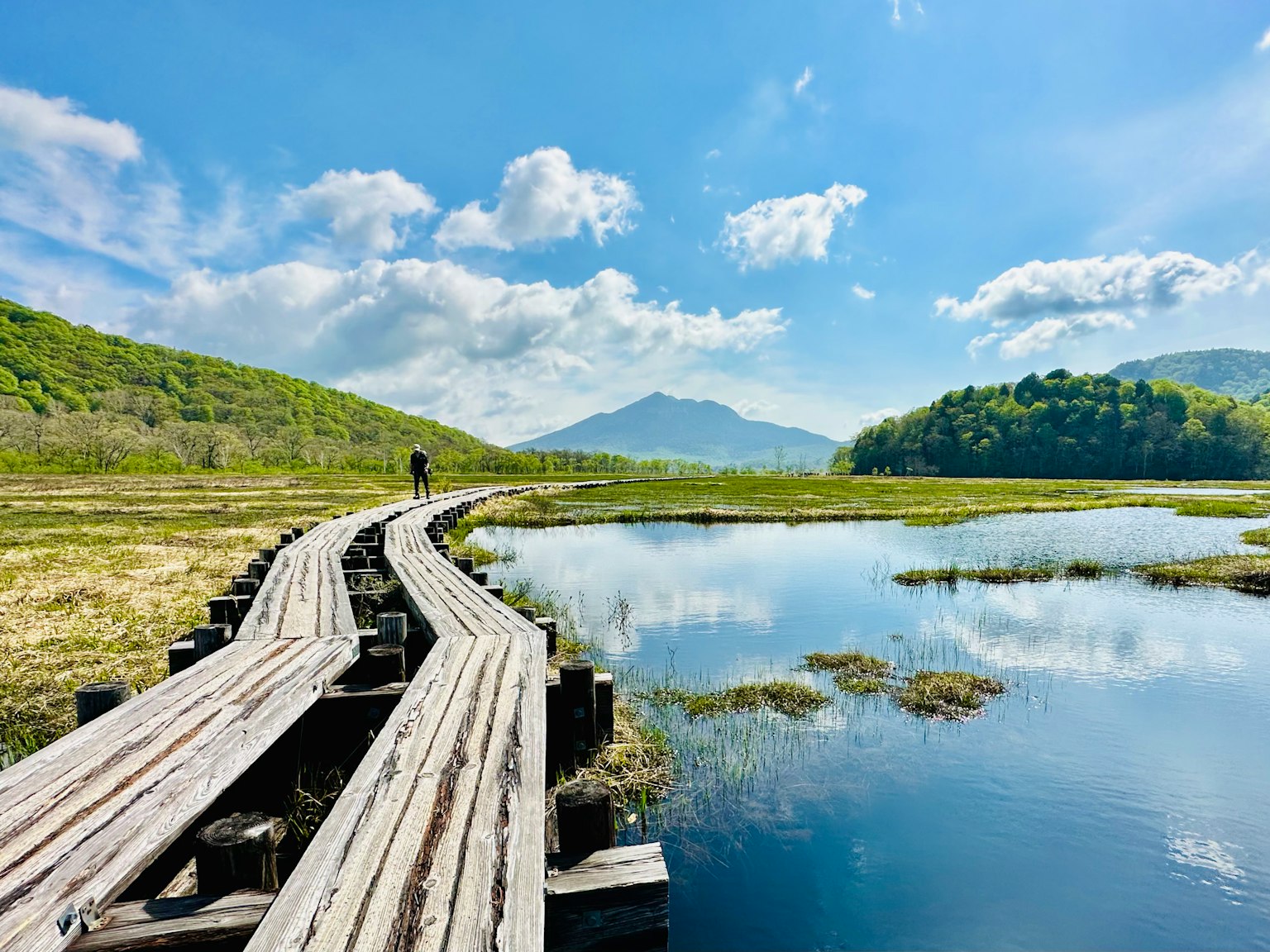 Sentiero in legno circondato da colline lussureggianti e lago tranquillo