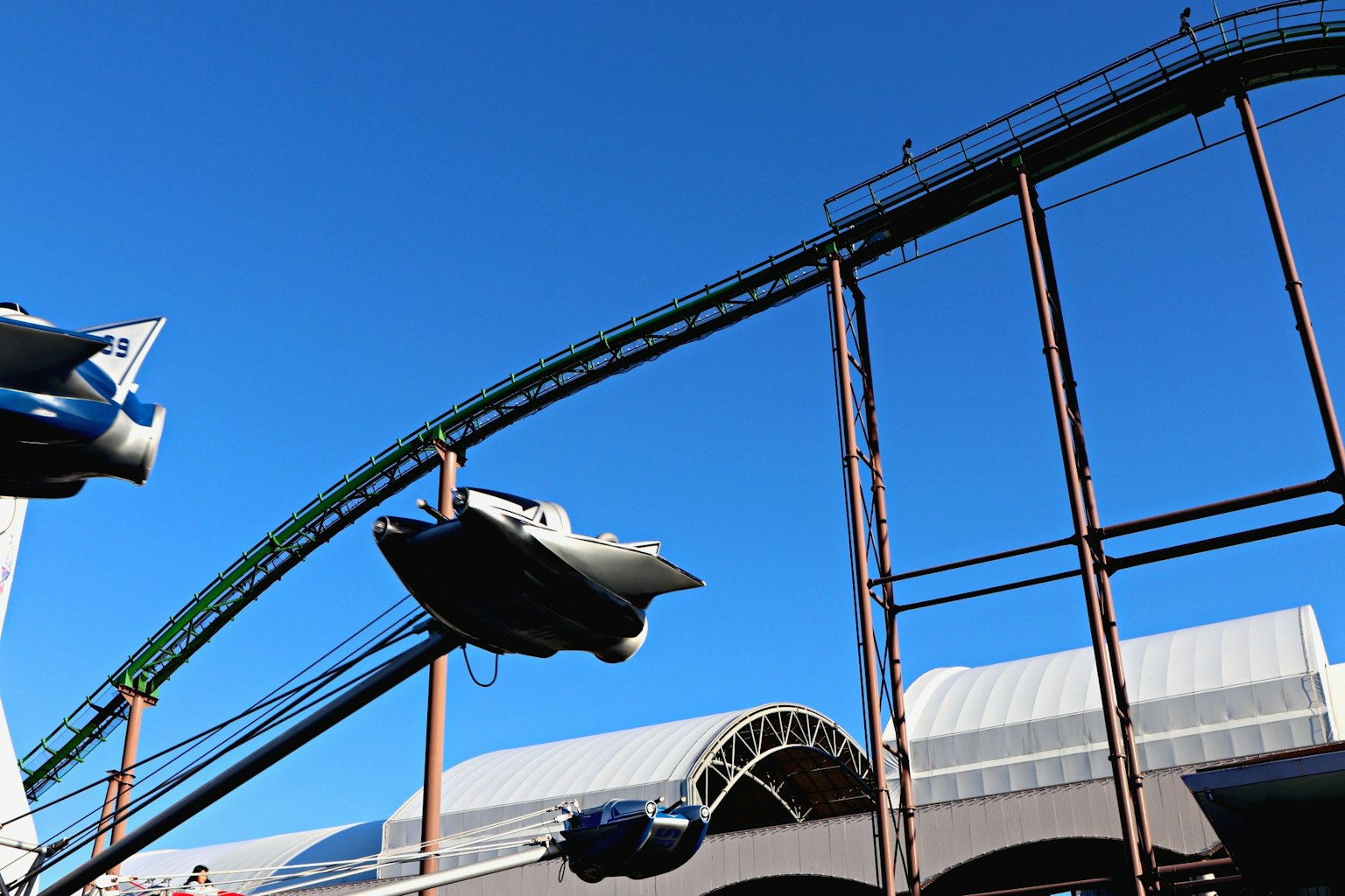 Roller coaster structure with vehicles under a clear blue sky