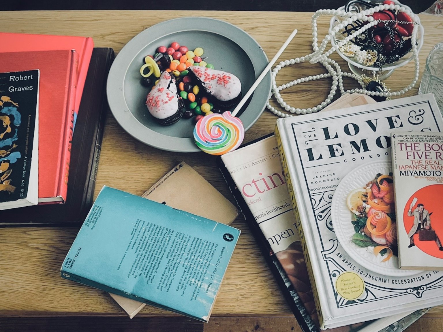 Une assiette de dessert garnie de bonbons colorés au centre entourée de divers livres et magazines