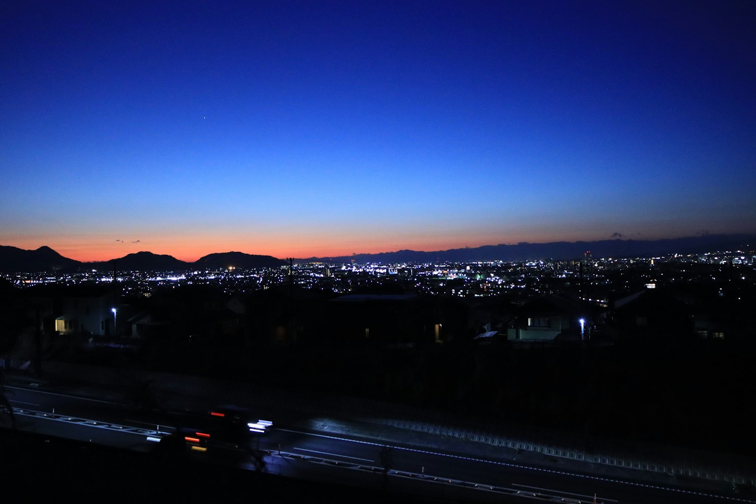 Twilight cityscape with silhouetted mountains