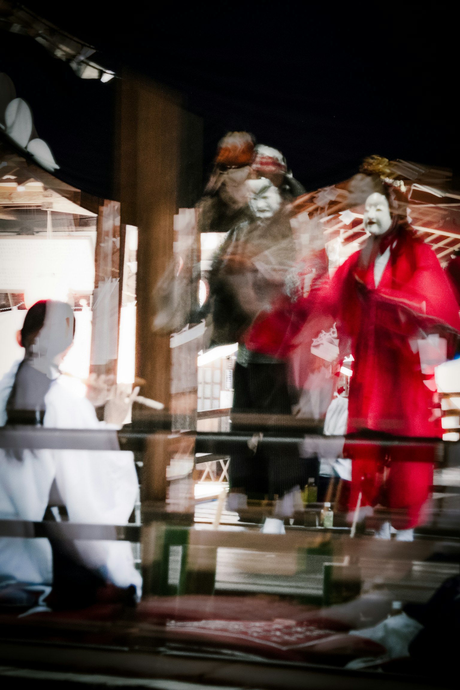 Personaggi in costumi rossi e bianchi che si esibiscono su un palco di Kagura