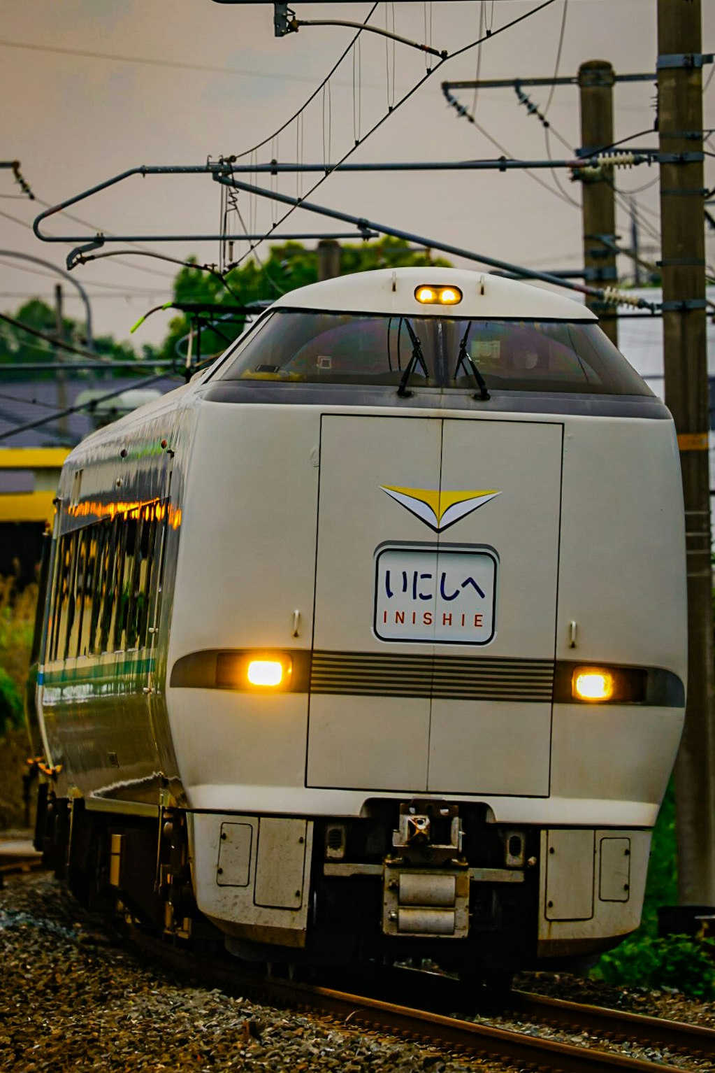 Tampak depan kereta ekspres dengan tulisan “いにしへ” berhenti di rel