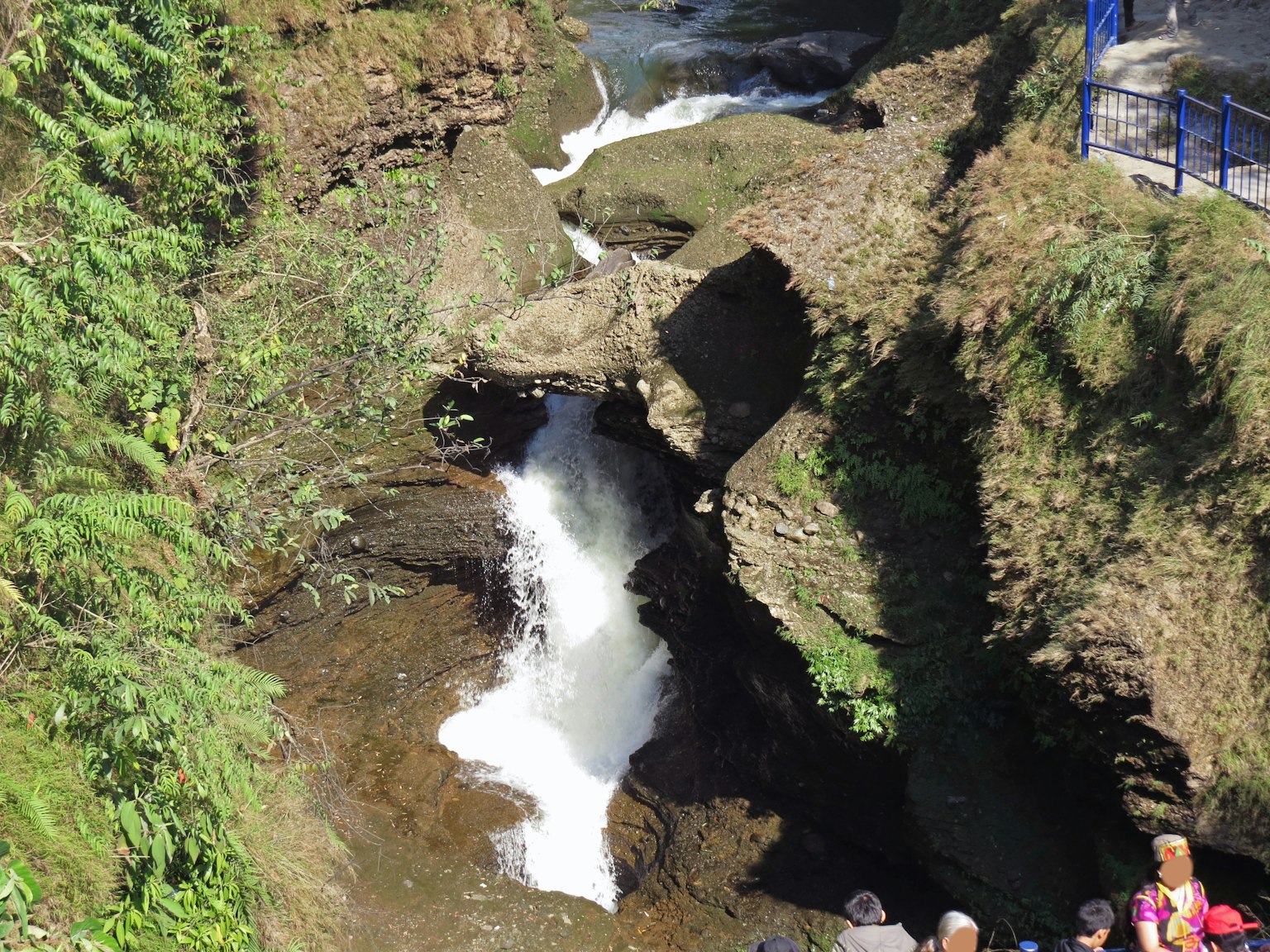 Air terjun yang indah dikelilingi batu dengan orang-orang di dekatnya
