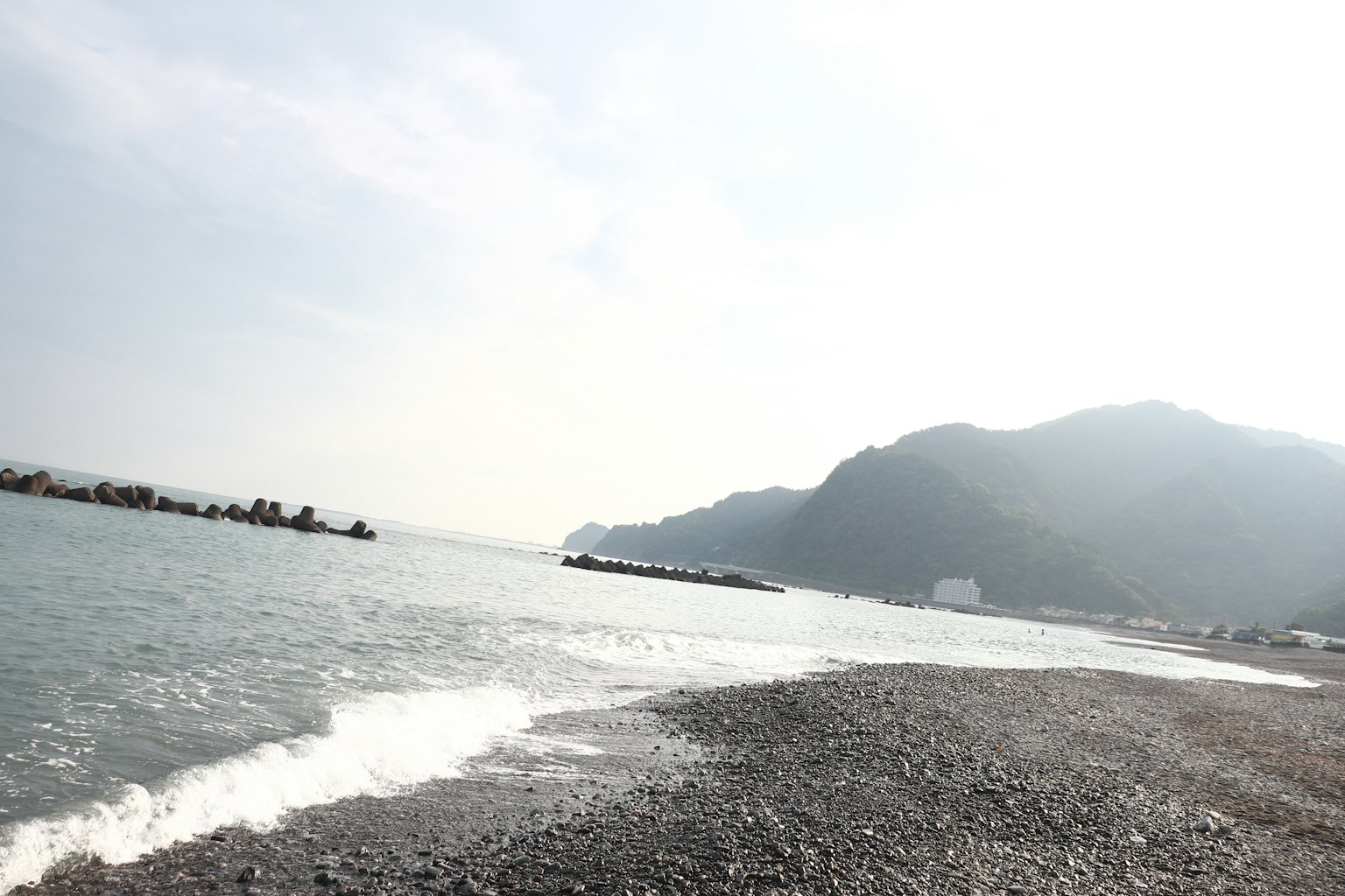 Pemandangan pantai dengan tepi berbatu dan ombak lembut