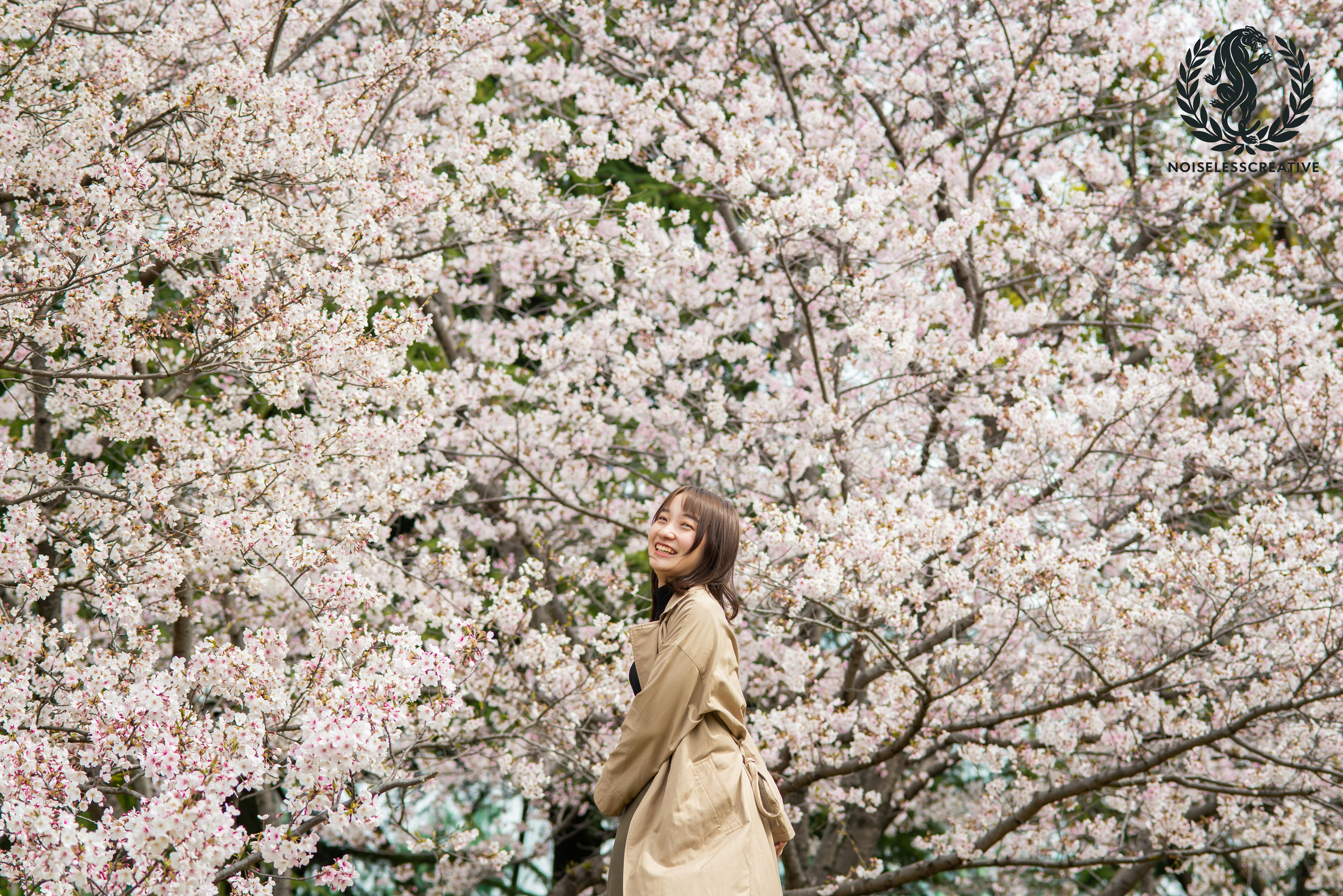 桜の花が咲く木の下で微笑む女性
