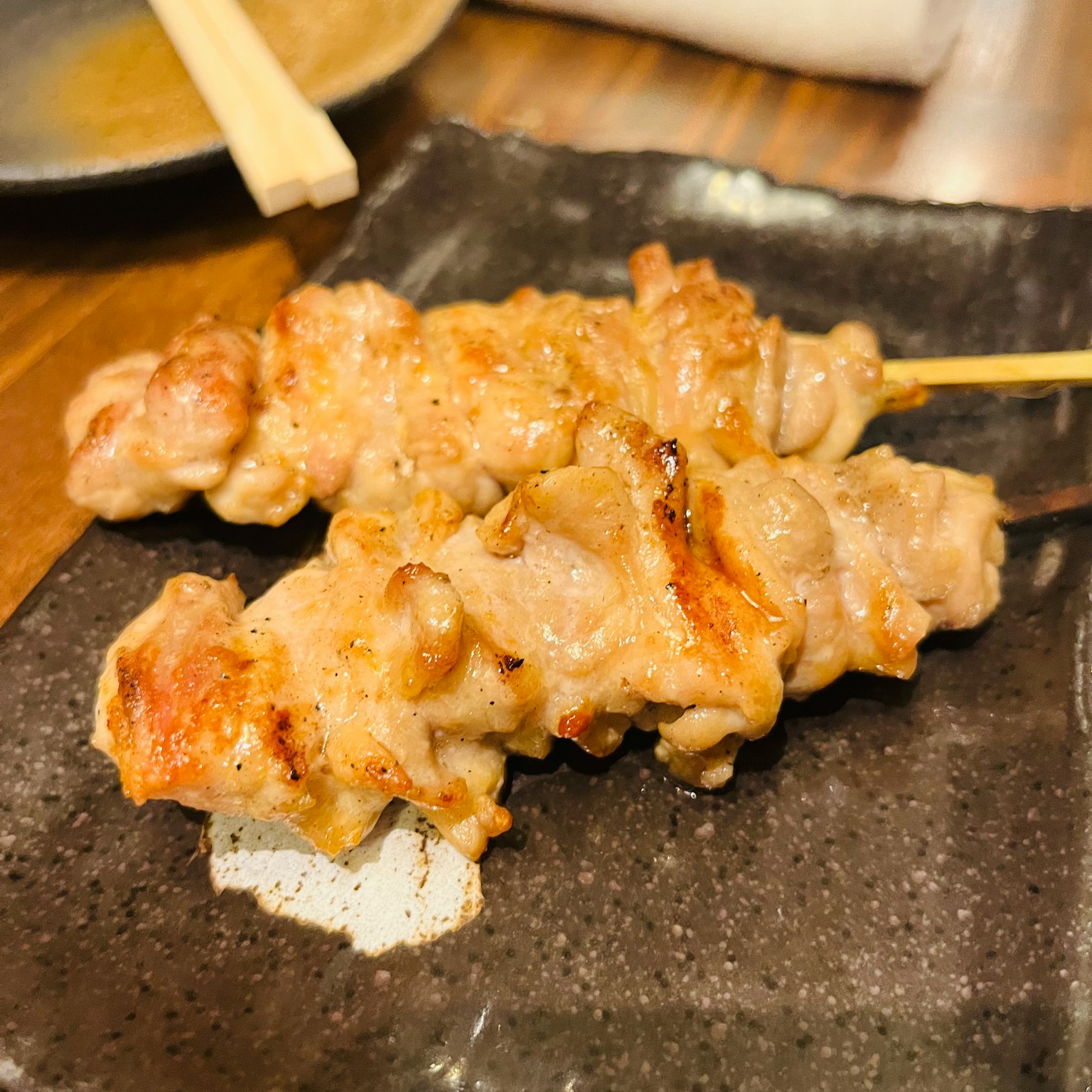 Brochettes de poulet grillées présentées sur une assiette noire