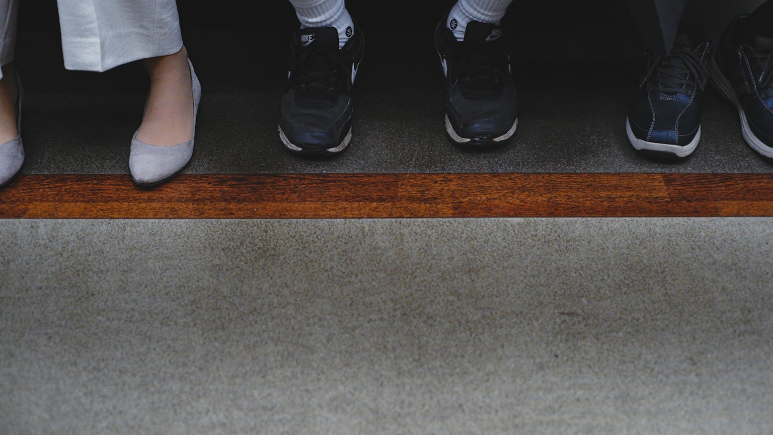 Adegan yang menampilkan sepatu dan kaki berjejer dengan tepi kayu yang khas