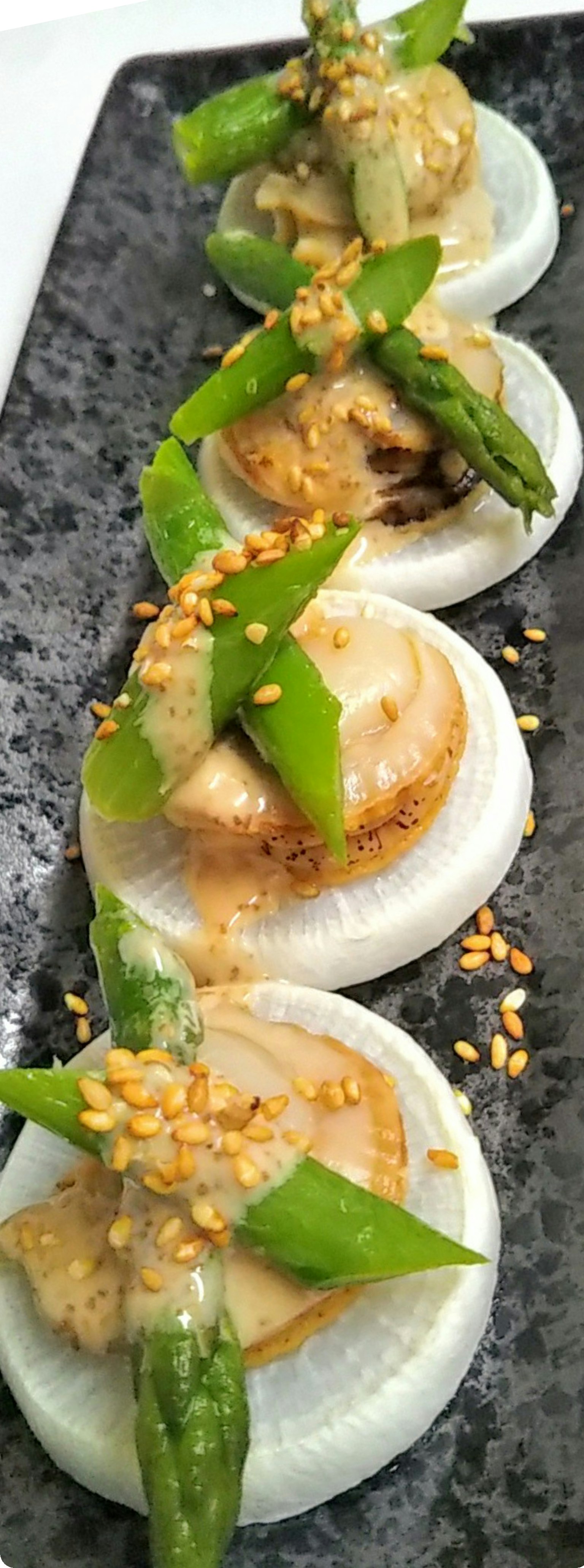 Plat avec des asperges et garniture de sésame servi sur une assiette blanche