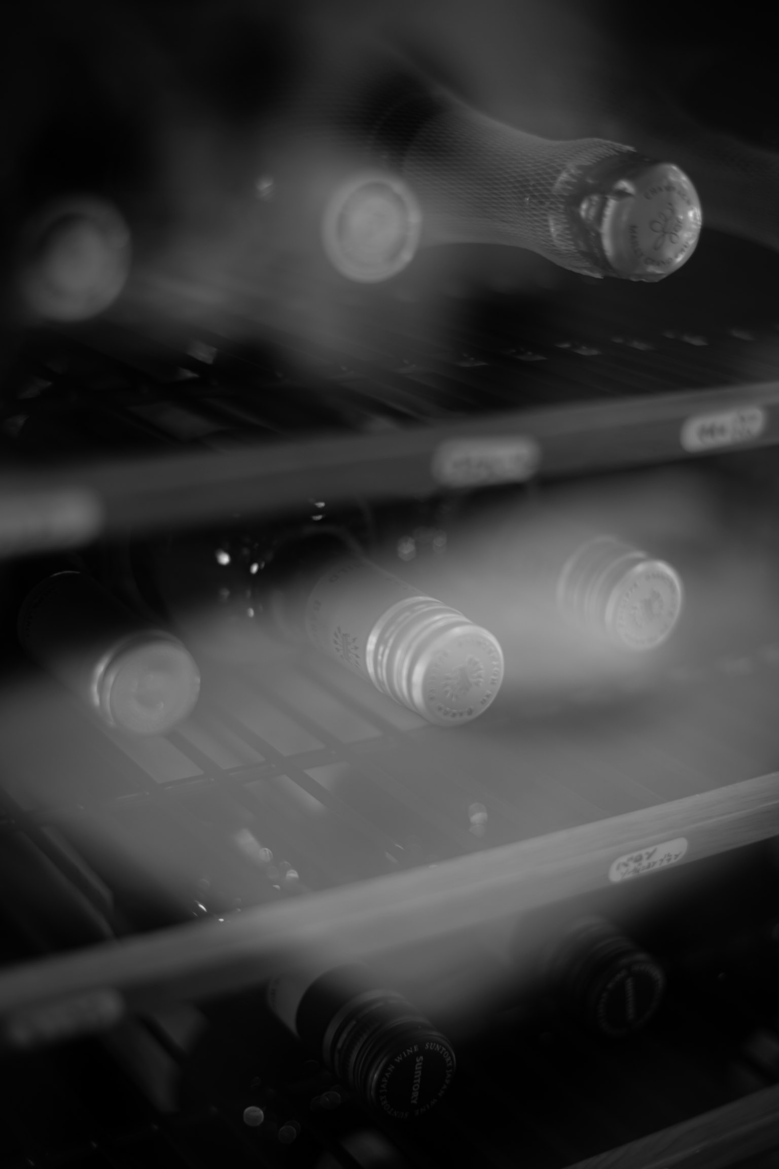 Close-up of wine bottles arranged inside a black and white wine cellar