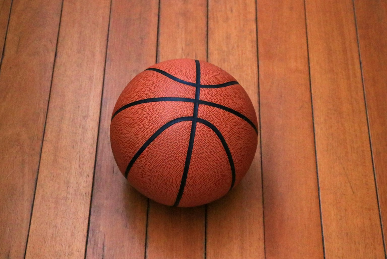 Sebuah bola basket yang terletak di lantai kayu
