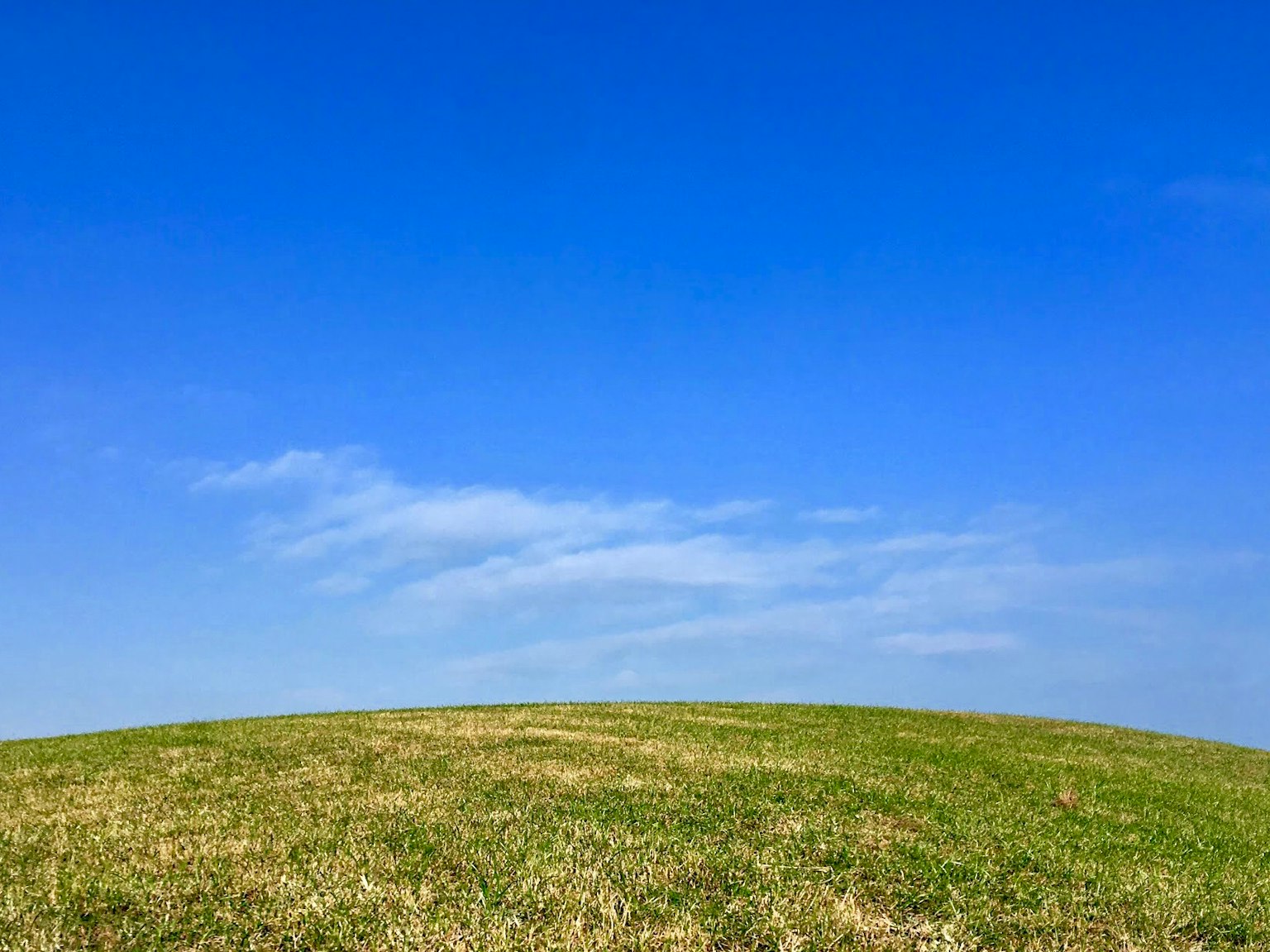 Un paesaggio con cielo blu e una collina verde