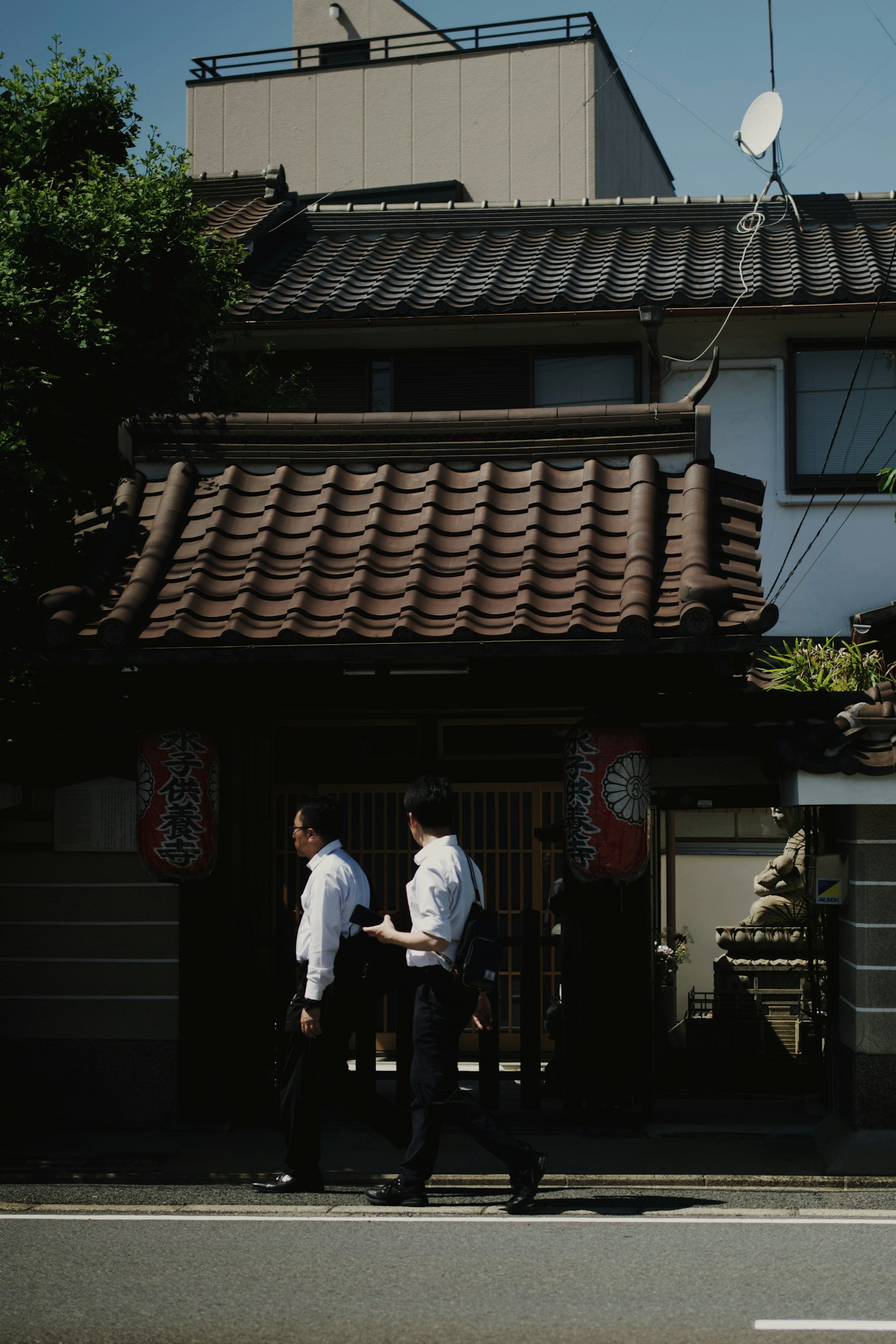 Dos hombres caminando frente a una casa japonesa tradicional