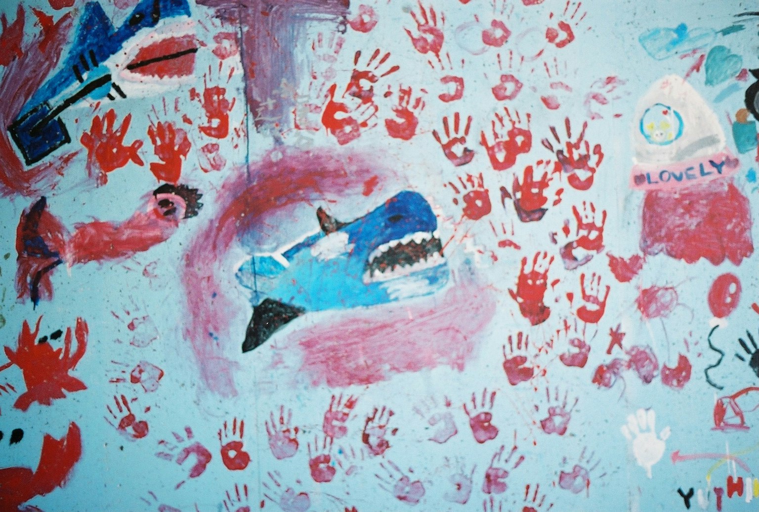 青い壁に描かれた魚や手形のアート作品