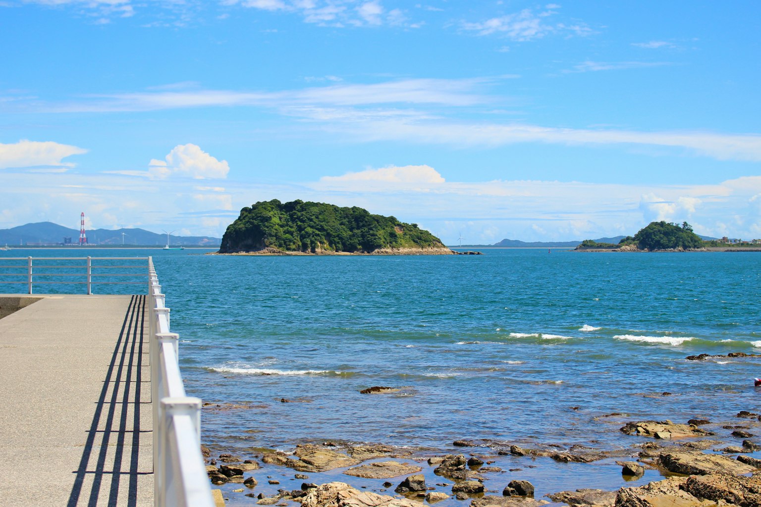 ทิวทัศน์ที่สวยงามของท่าเรือพร้อมทะเลสีน้ำเงินและเกาะในพื้นหลัง