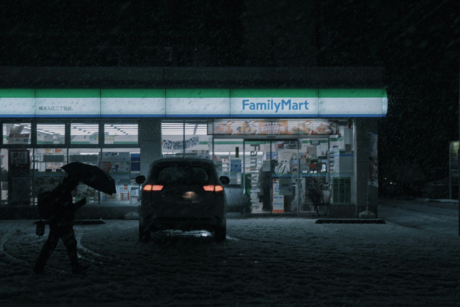 Tienda FamilyMart iluminada por la noche con una persona que sostiene un paraguas