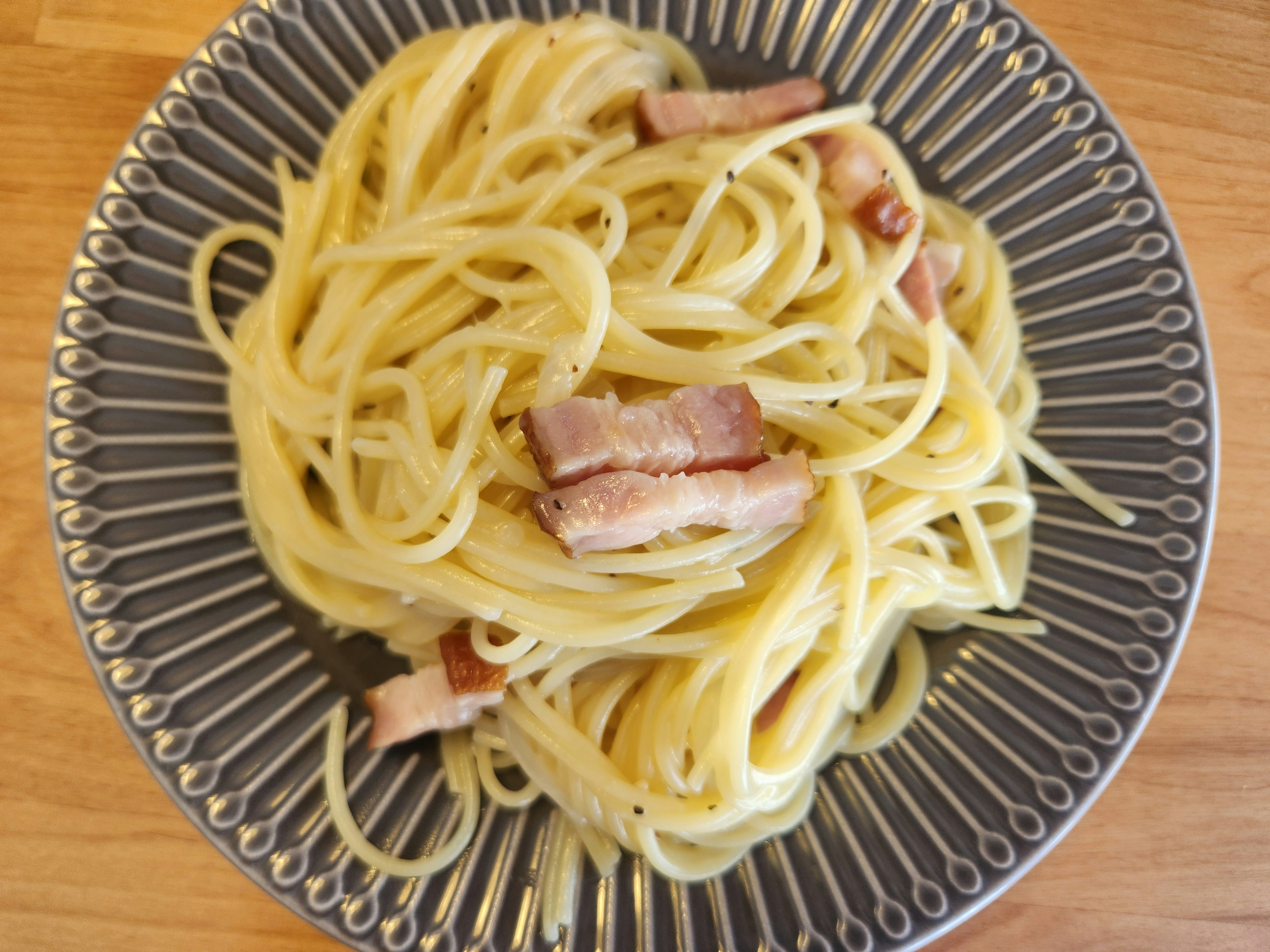 皿に盛られたベーコン入りパスタ