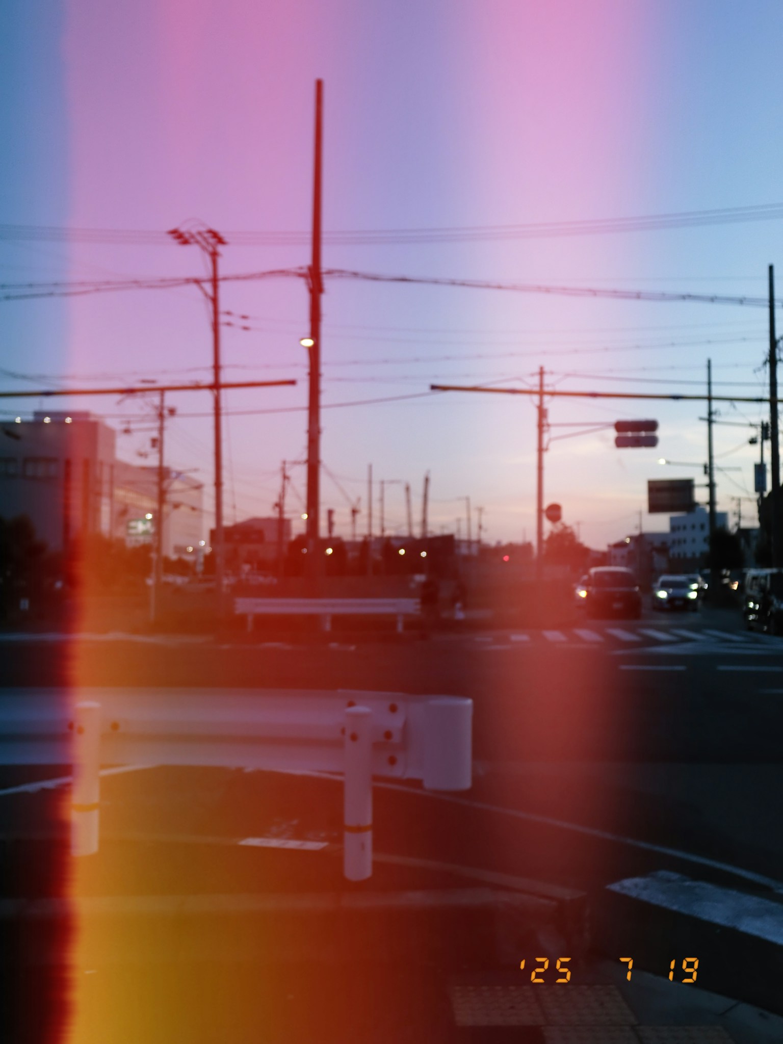 Escena de calle al atardecer con postes de luz y señales de tráfico visibles coches en la carretera