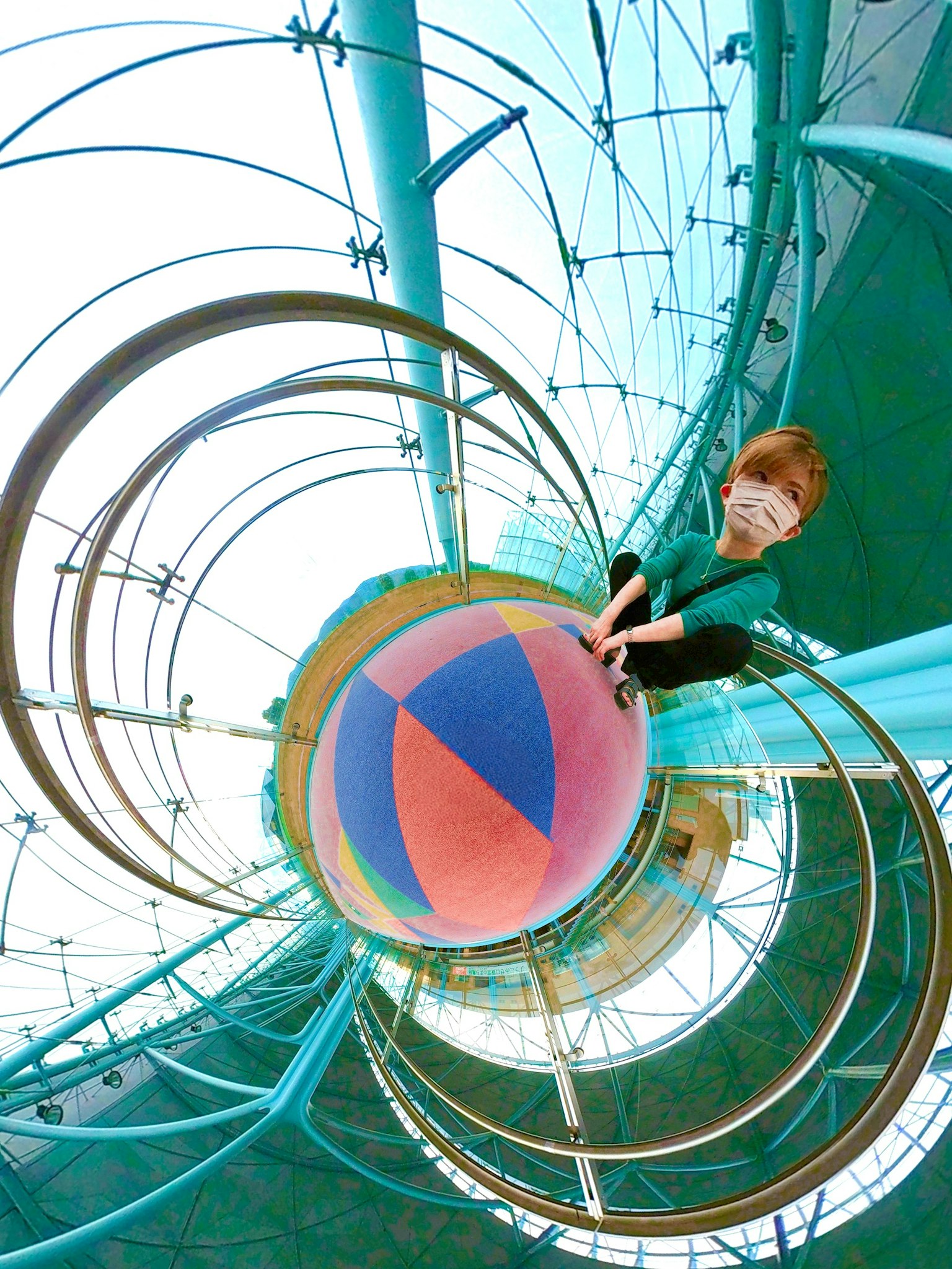 Un niño sentado sobre una bola colorida dentro de una estructura futurista que resalta colores vibrantes y un diseño único