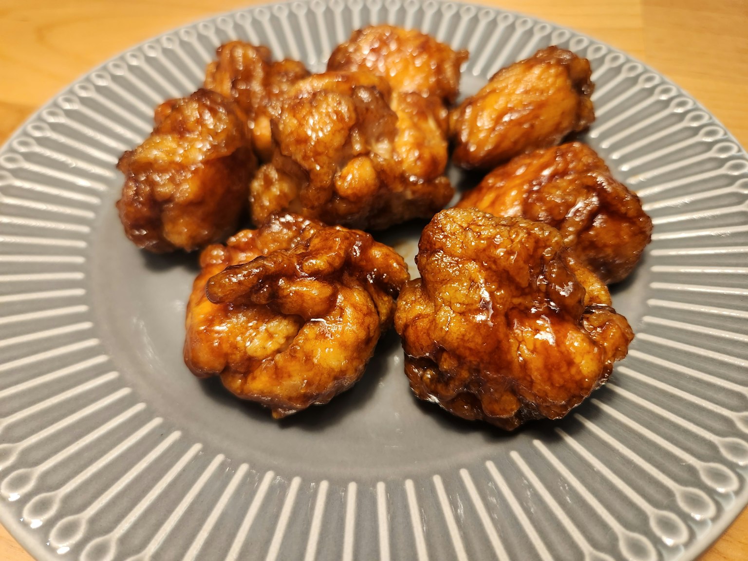 Potongan ayam goreng yang lezat dilapisi saus di atas piring dekoratif
