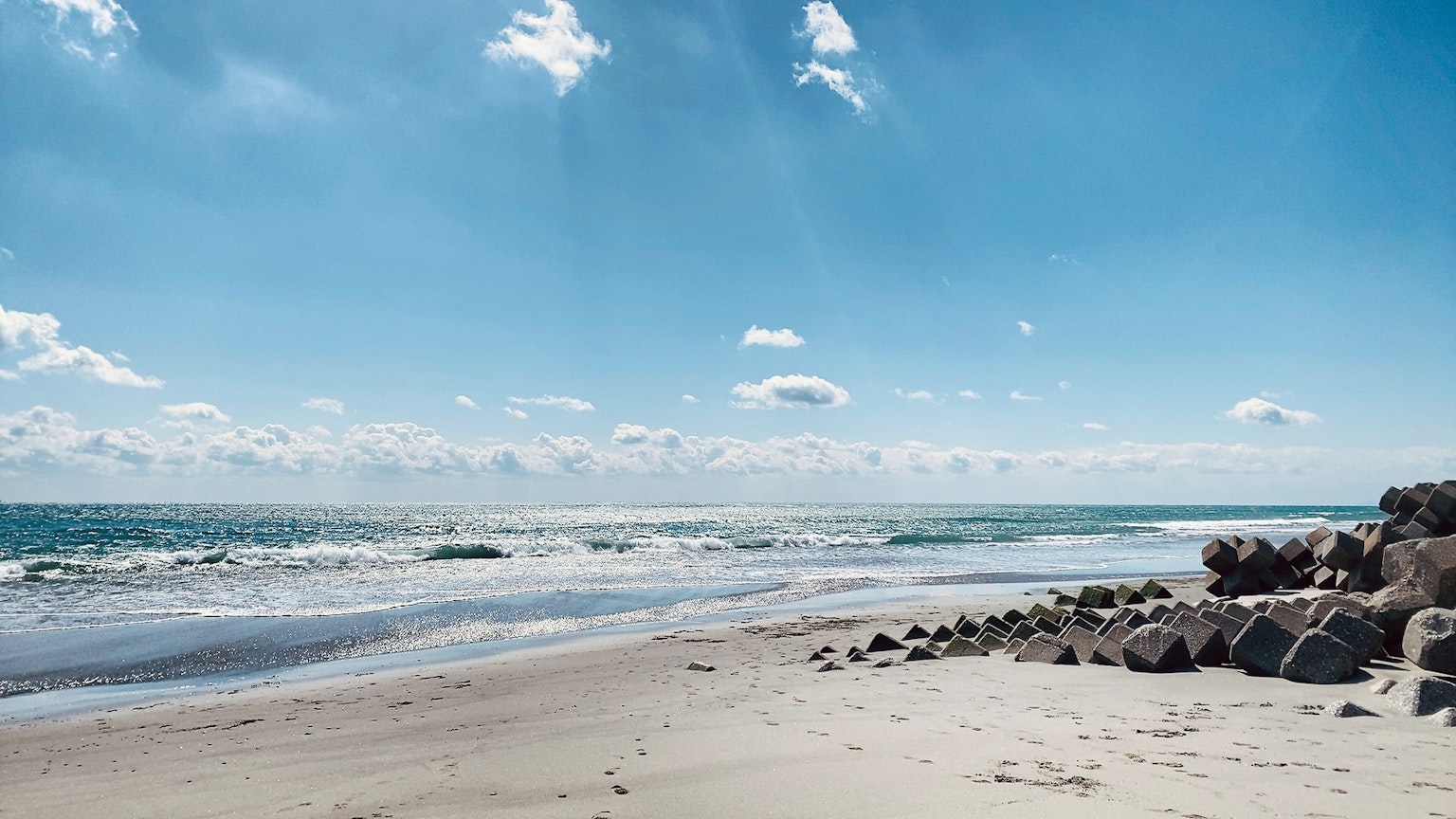 Malersiche Strandansicht mit blauem Himmel und weißen Wolken felsige Küste im Vordergrund